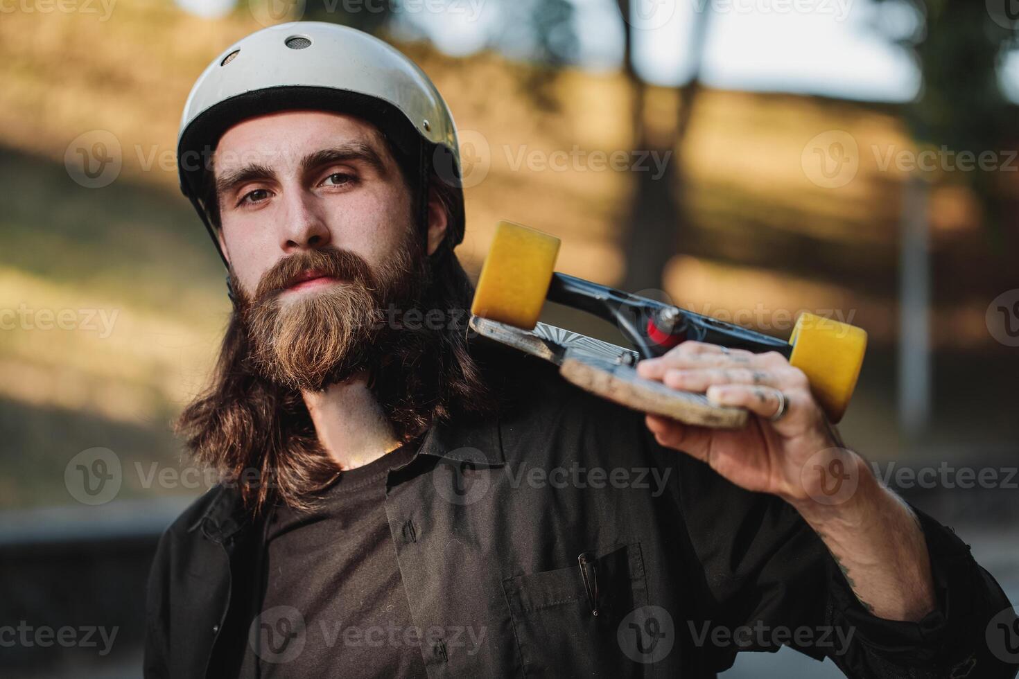 Portrait of a bearded guy with a skateboard, a longboard in his hands. photo