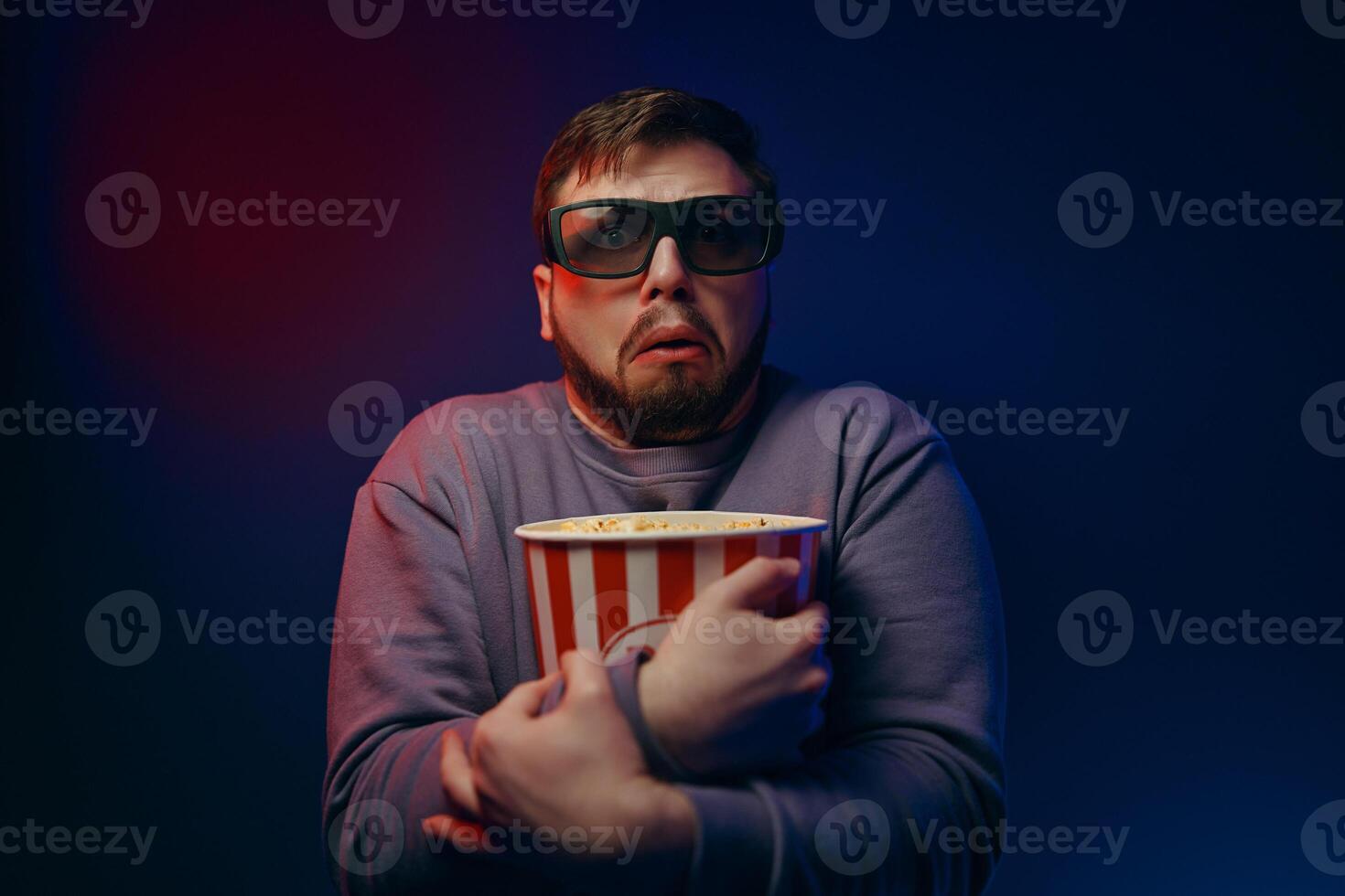 A man in 3D glasses and popcorn is watching a movie. photo
