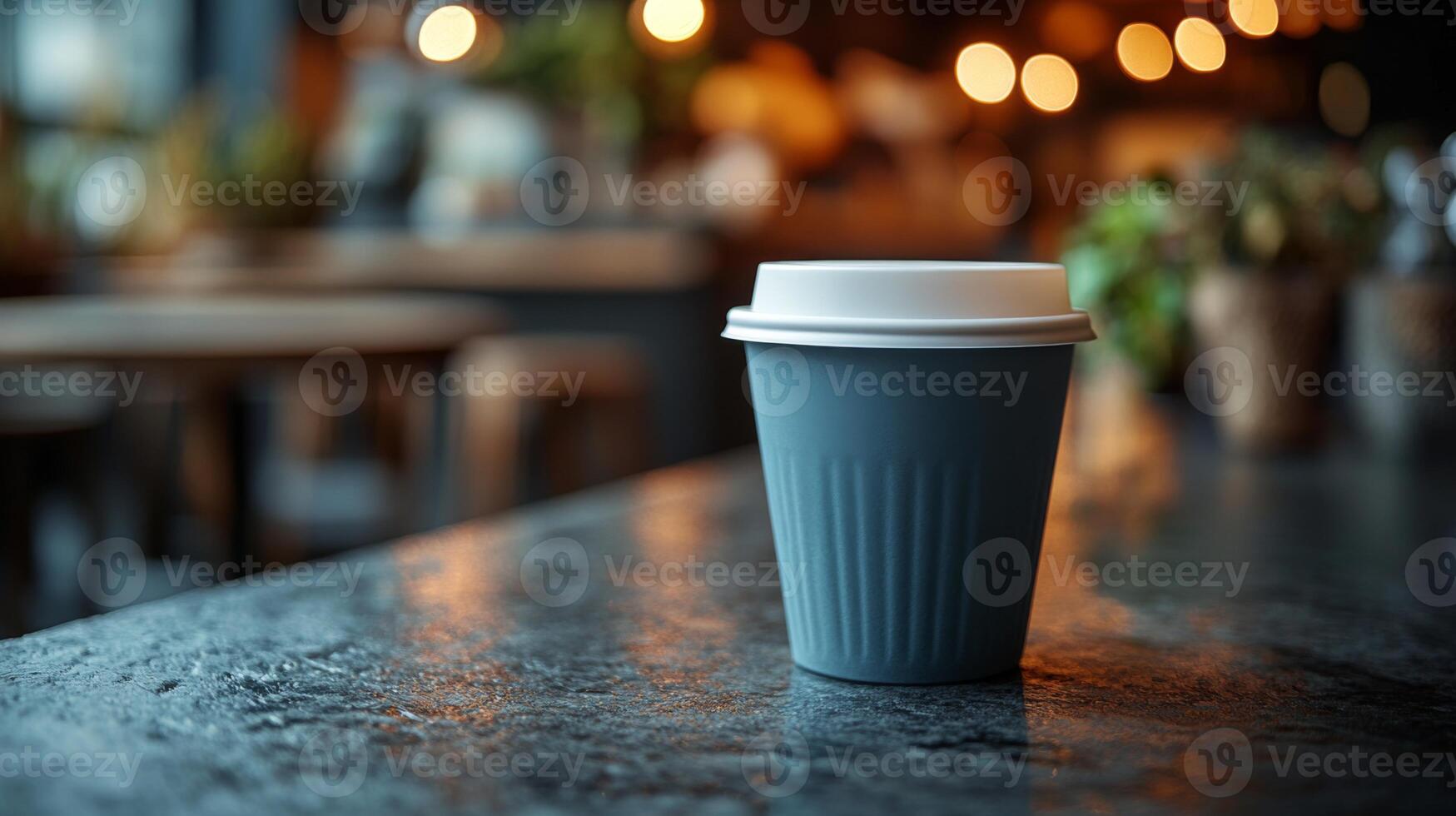 A warm coffee cup is placed on a textured dark table inside a cozy cafe. The soft glow of ambient lighting enhances the inviting atmosphere, perfect for relaxation or conversation. photo