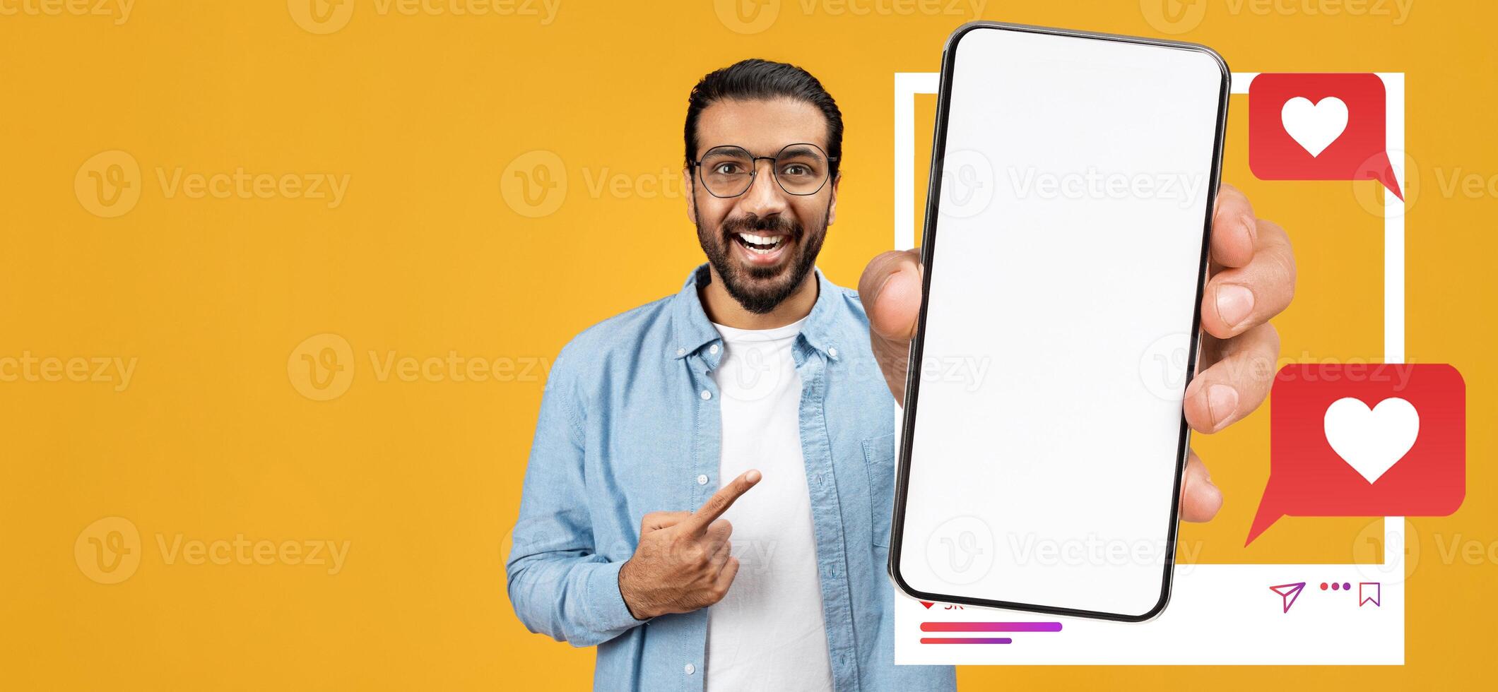 An influencer smiles and points at a smartphone showcasing a blank screen, surrounded by social media elements. The vibrant yellow background enhances the lively atmosphere of online engagement. photo