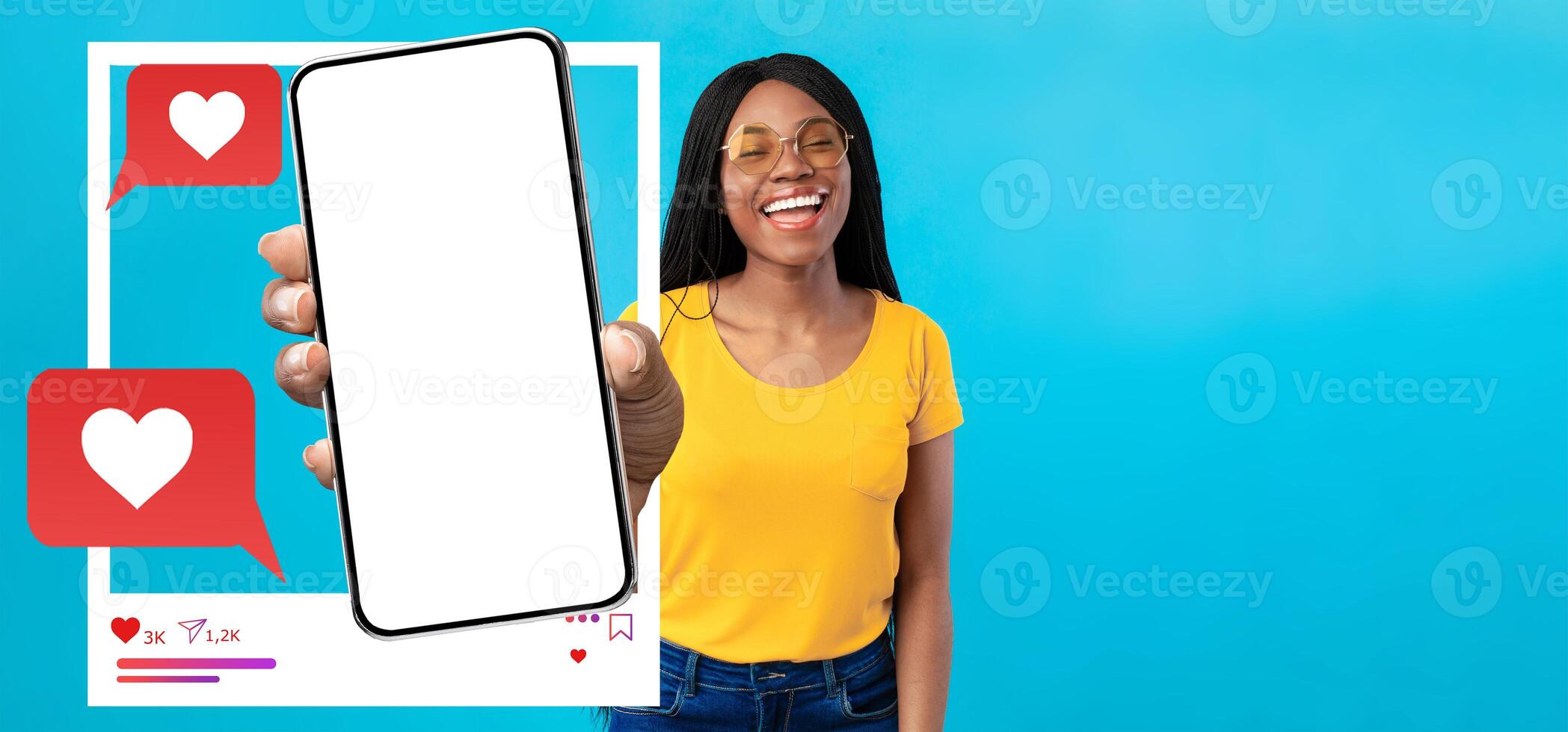 A cheerful influencer holds up a smartphone against a bright blue background. The device features empty social media icons, inviting engagement. She's smiling and ready to connect online. photo