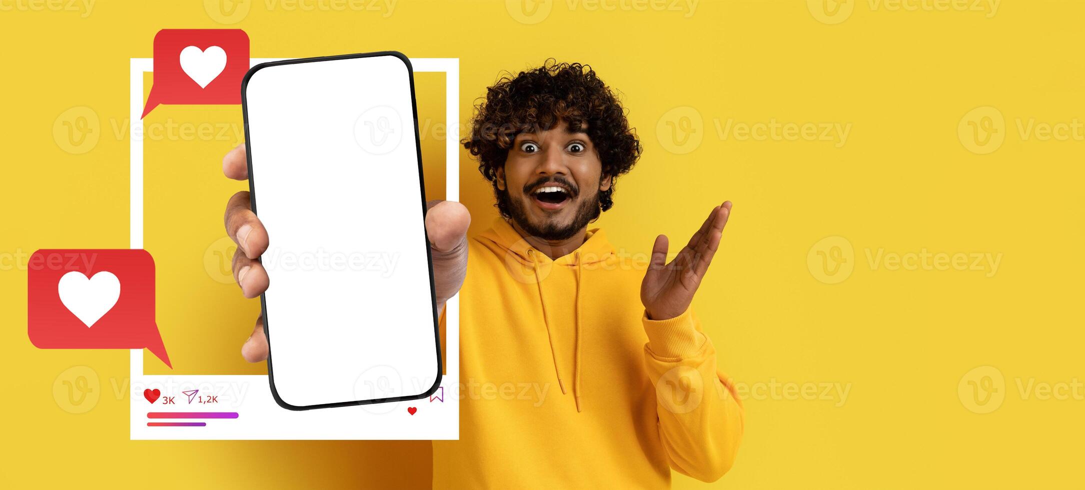 A cheerful influencer stands against a bright yellow background, holding a smartphone displaying a blank screen. photo