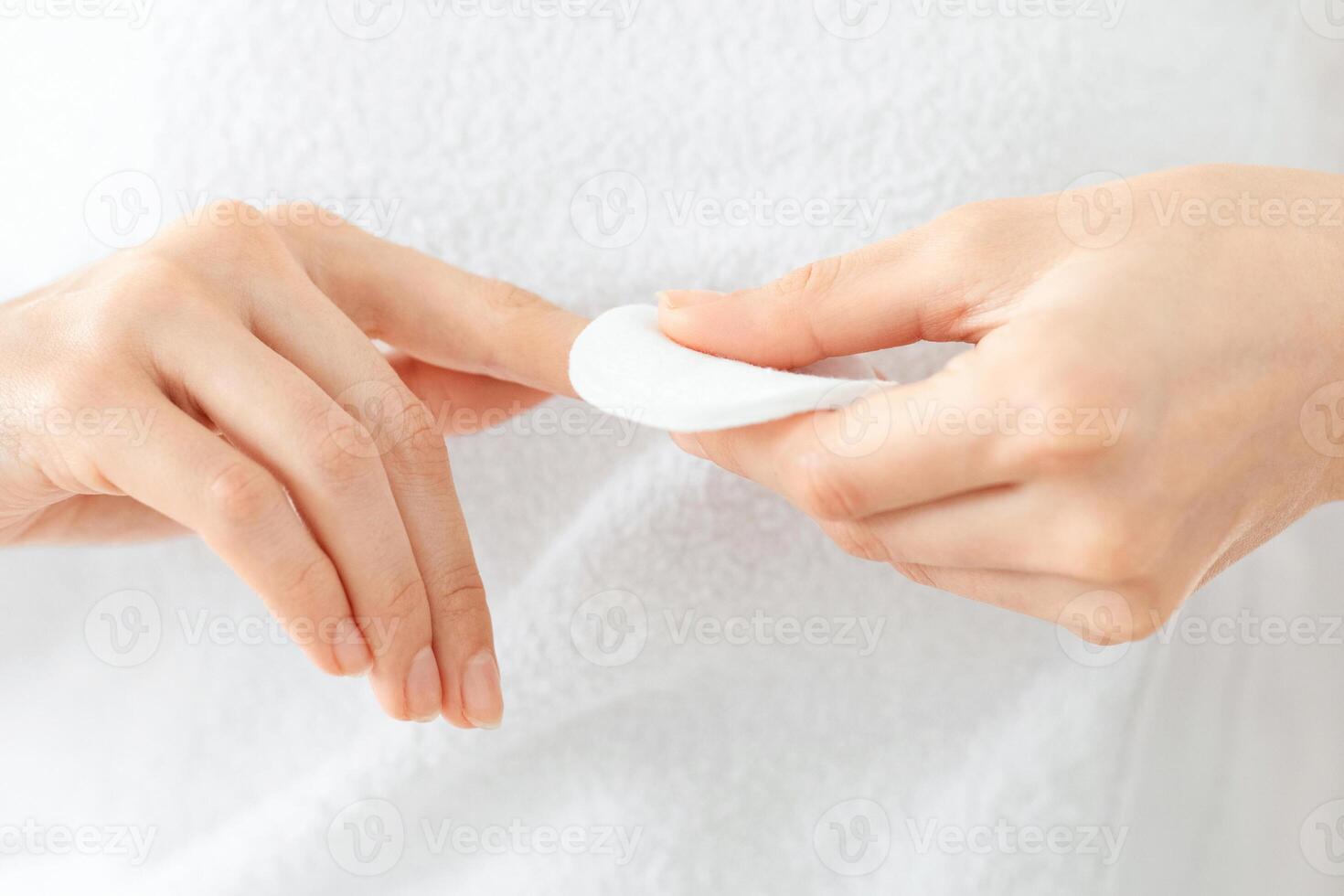 Unrecognizable woman removing lacquer from manicured nails with white cotton pad and acetone. Closeup of lady using nail polisher remover and cotton pad, making manicure at home, cropped photo