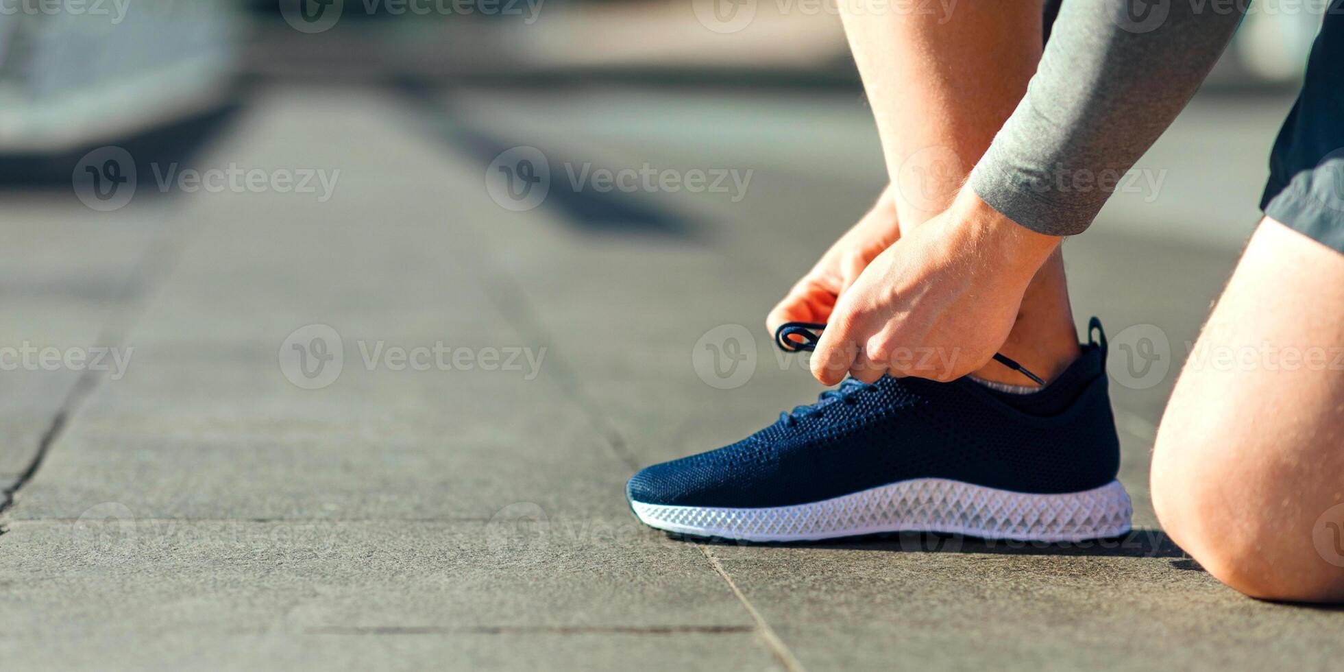 Get ready for training. Guy tying laces on sneakers at stadium, cropped, close up, free space photo