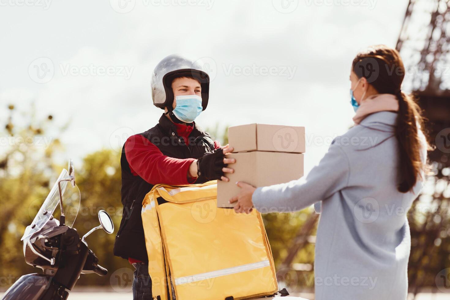 Safe Delivery. Courier Delivering Food Boxes From Restaurants And Cafe On Motorbike, Wearing Medical Mask Outdoor. photo