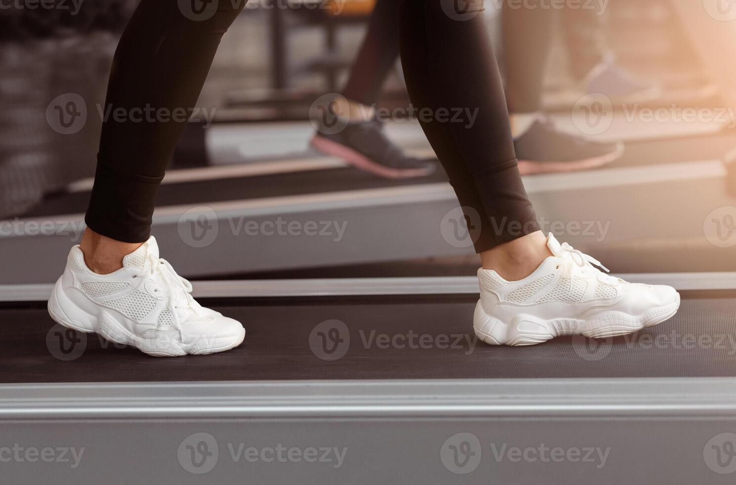 A person walks steadily on a treadmill in a modern gym, focusing on their workout. The atmosphere is energetic and designed for fitness enthusiasts. photo