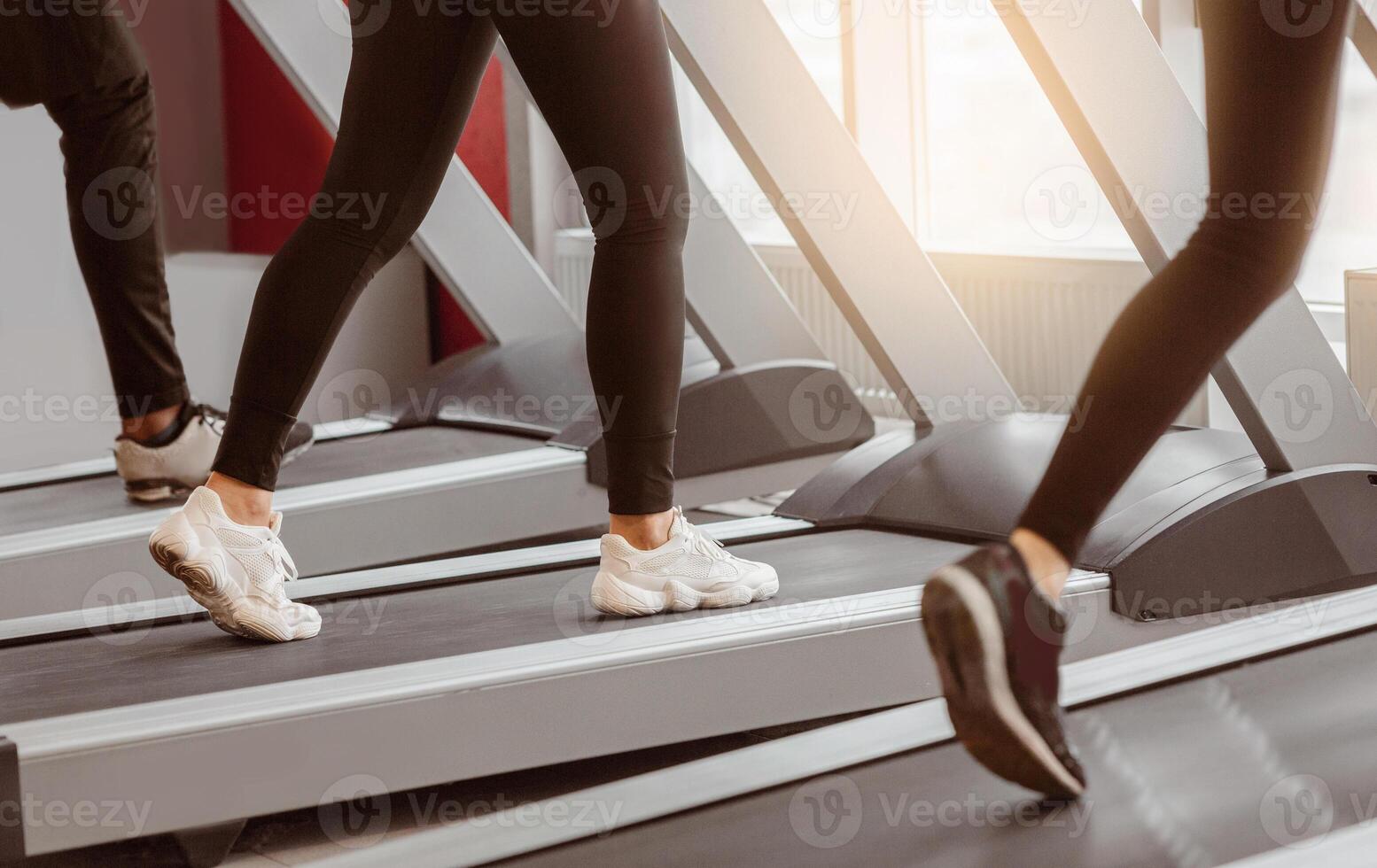 Two individuals are engaged in a treadmill workout at a contemporary gym, showcasing their commitment to fitness. Morning light streams through the windows, enhancing the atmosphere of motivation. photo