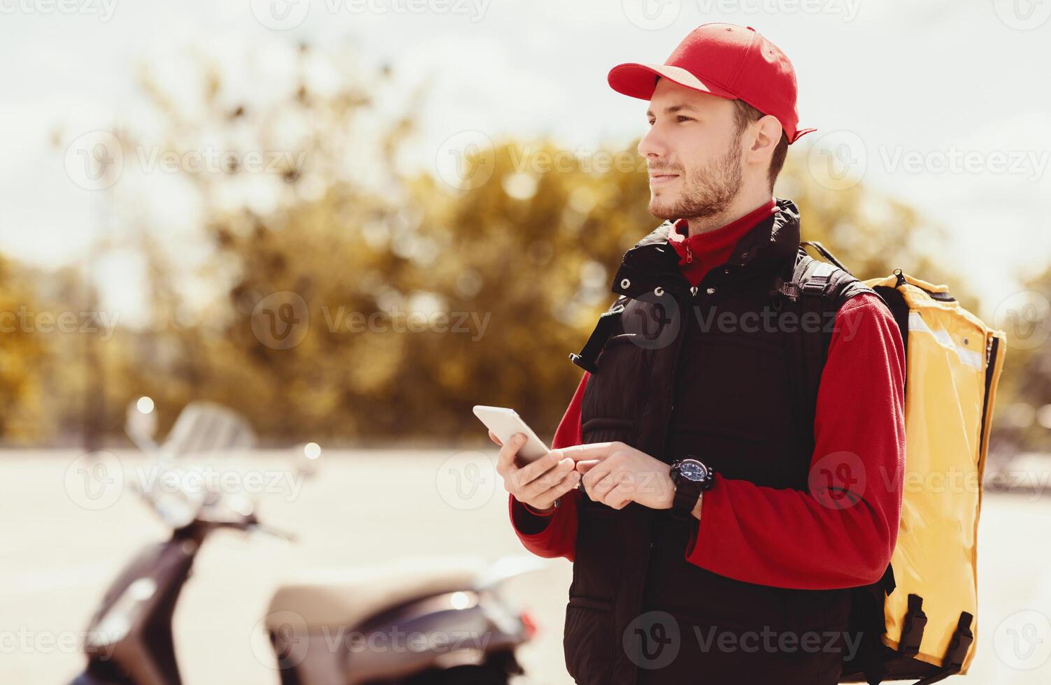 Delivery Application. Courier Using Cellphone App Delivering Food On Motorbike Outside. Free Space photo