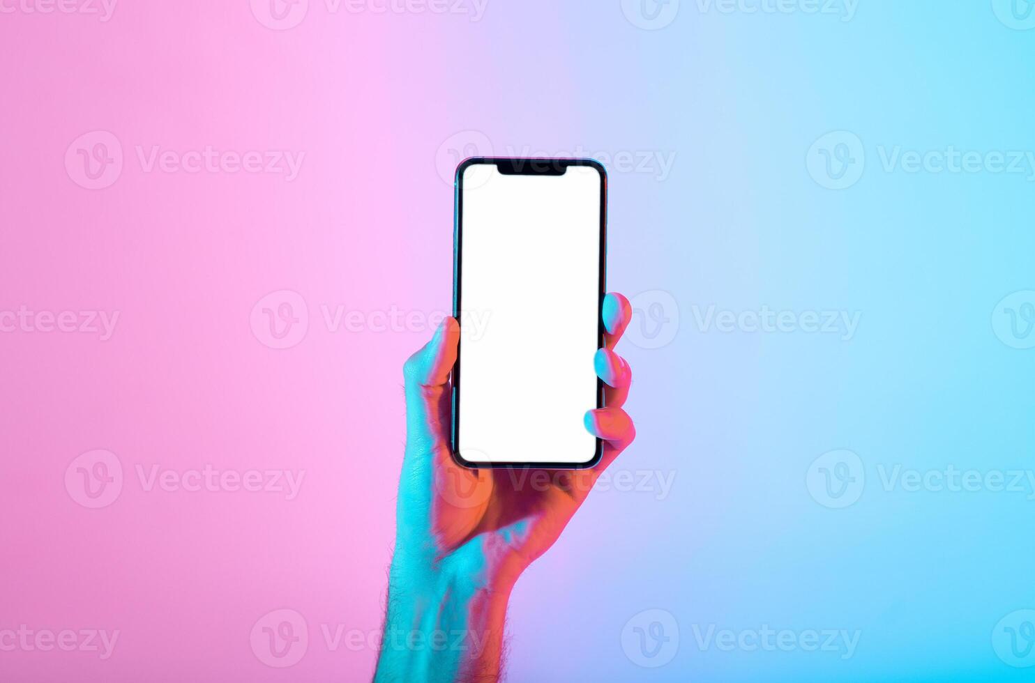 A hand presents a smartphone with a blank screen, set against a vibrant gradient backdrop of pink and blue colors. This moment highlights modern technology and minimalism. photo