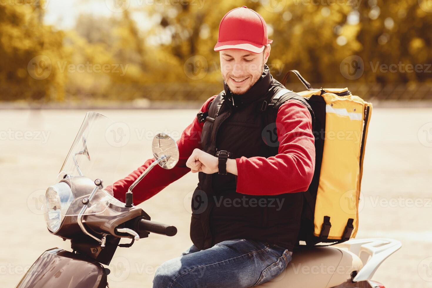 On-Time Delivery. Professional Courier Checking Time Looking At Watch Sitting On Scooter Outside. photo