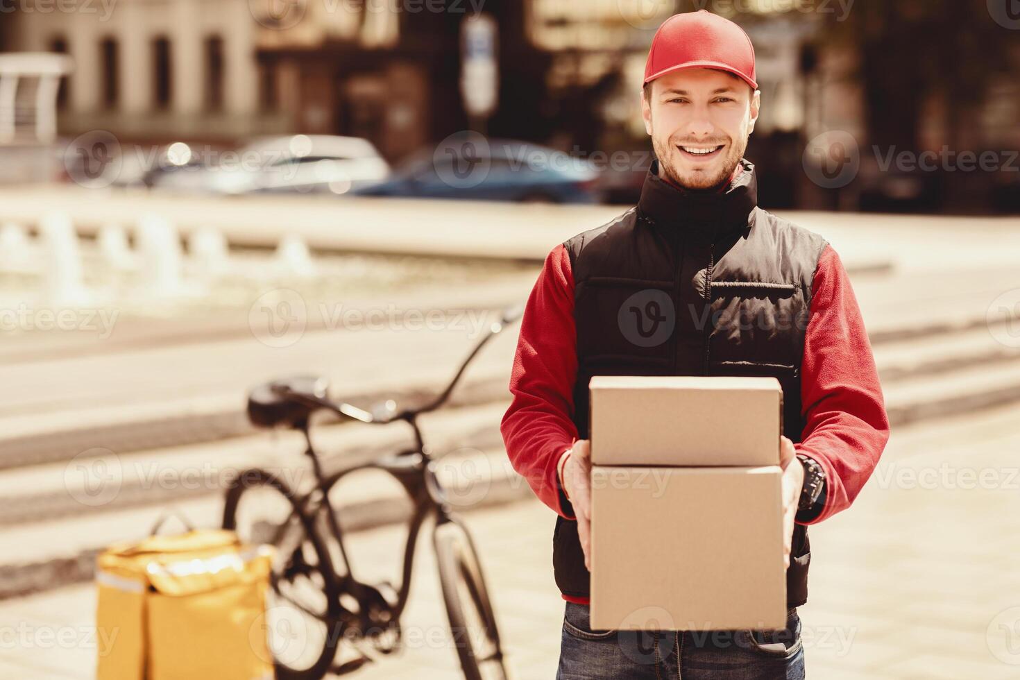 Fast Delivery. Happy Courier Holding Boxes Smiling To Camera Delivering Parcels In City. Blank Space photo