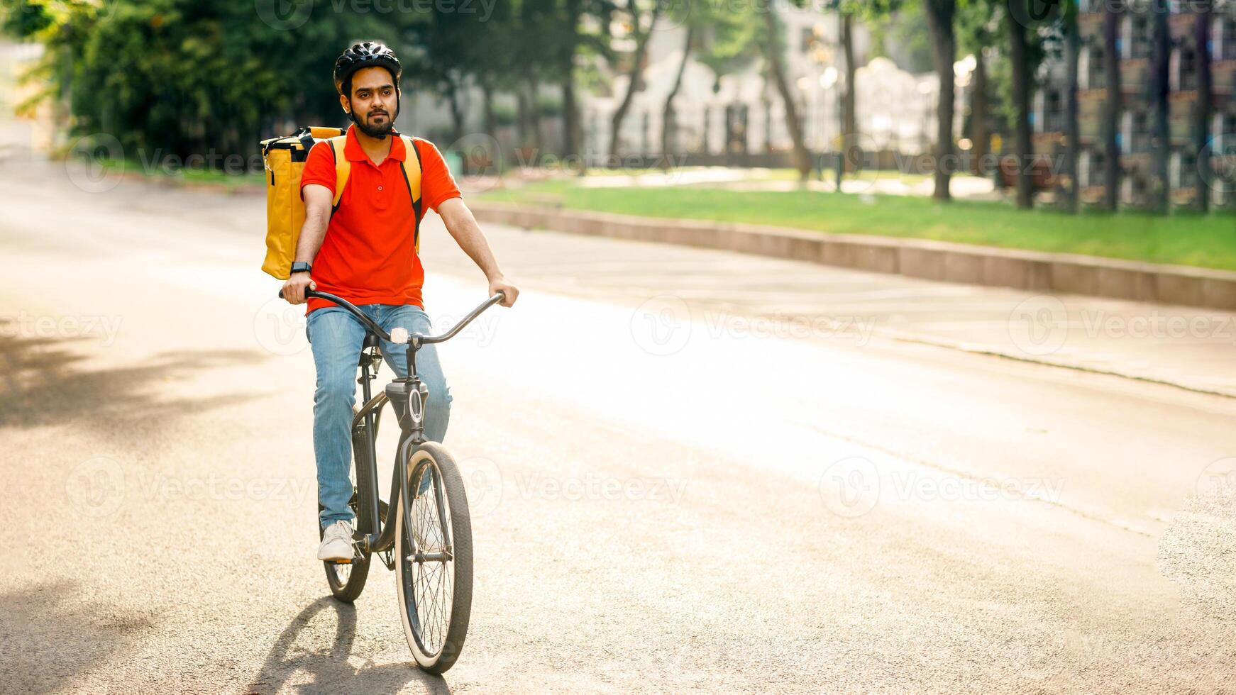 Modern delivery in city. Young man in helmet with yellow bag rides on bicycle on road to client photo