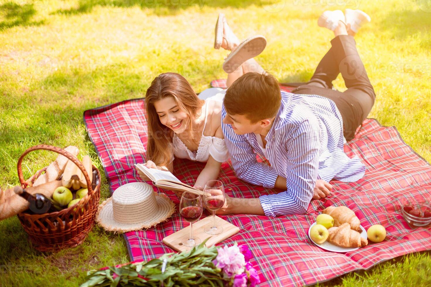 Loving married couple reading book together during picnic in countryside photo