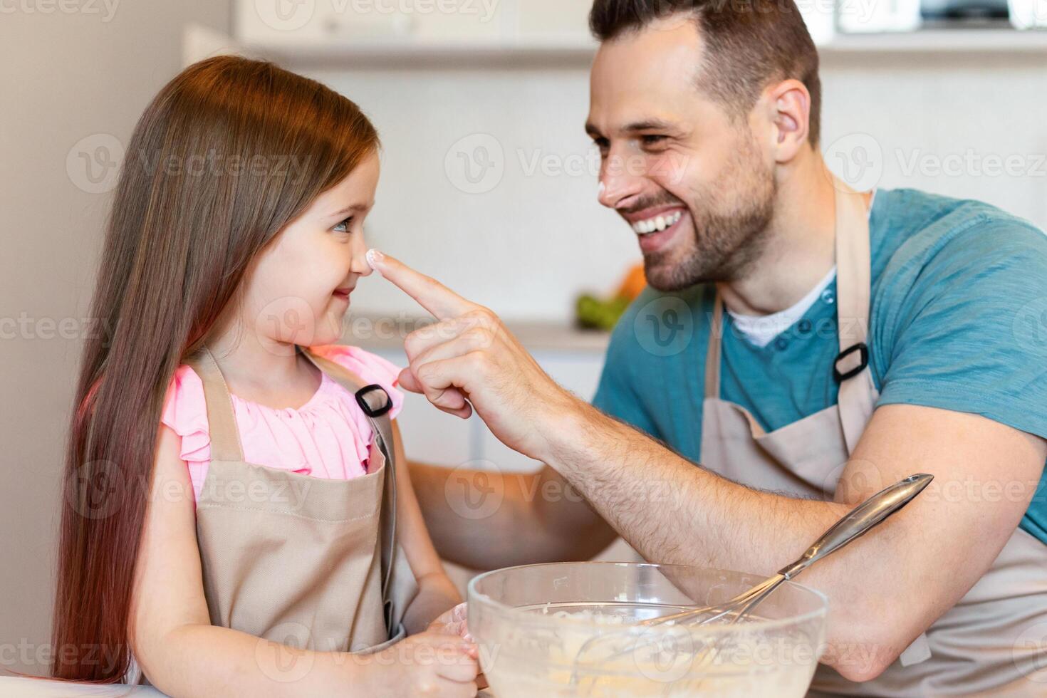 Happy Dad And Little Daughter Having Fun Baking Cookies, Daddy Playfully Touching Kid's Nose Fooling Together In Modern Kitchen At Home. Family Cooking Making Dough Enjoying Weekend photo