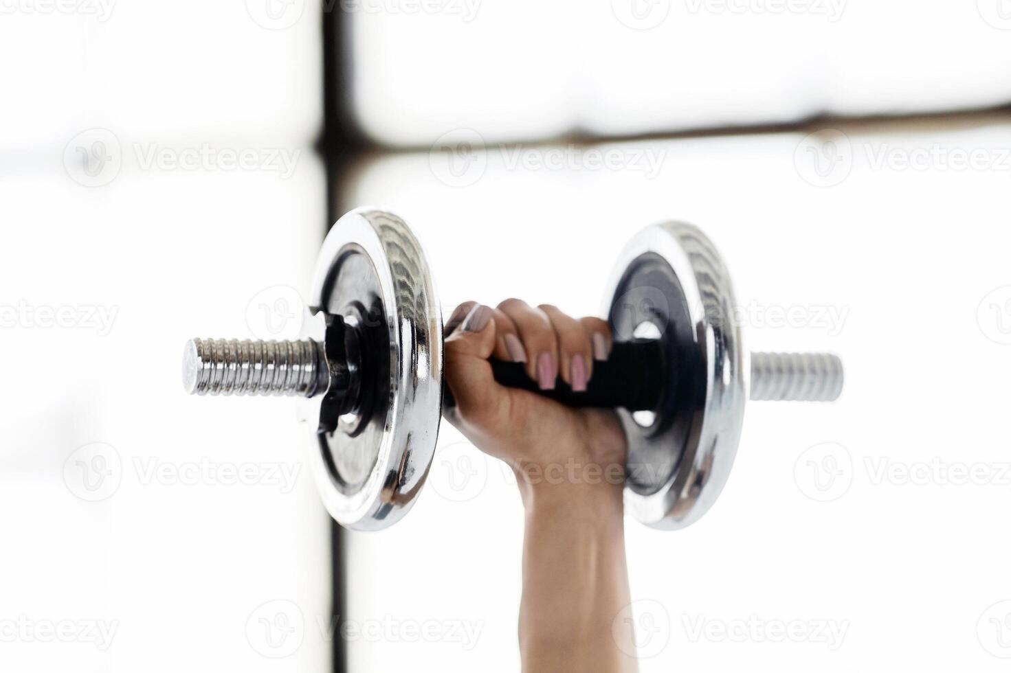 Exercise with dumbbells. Female hand holding sports equipment for training for biceps at gym or home, close up, copy space photo