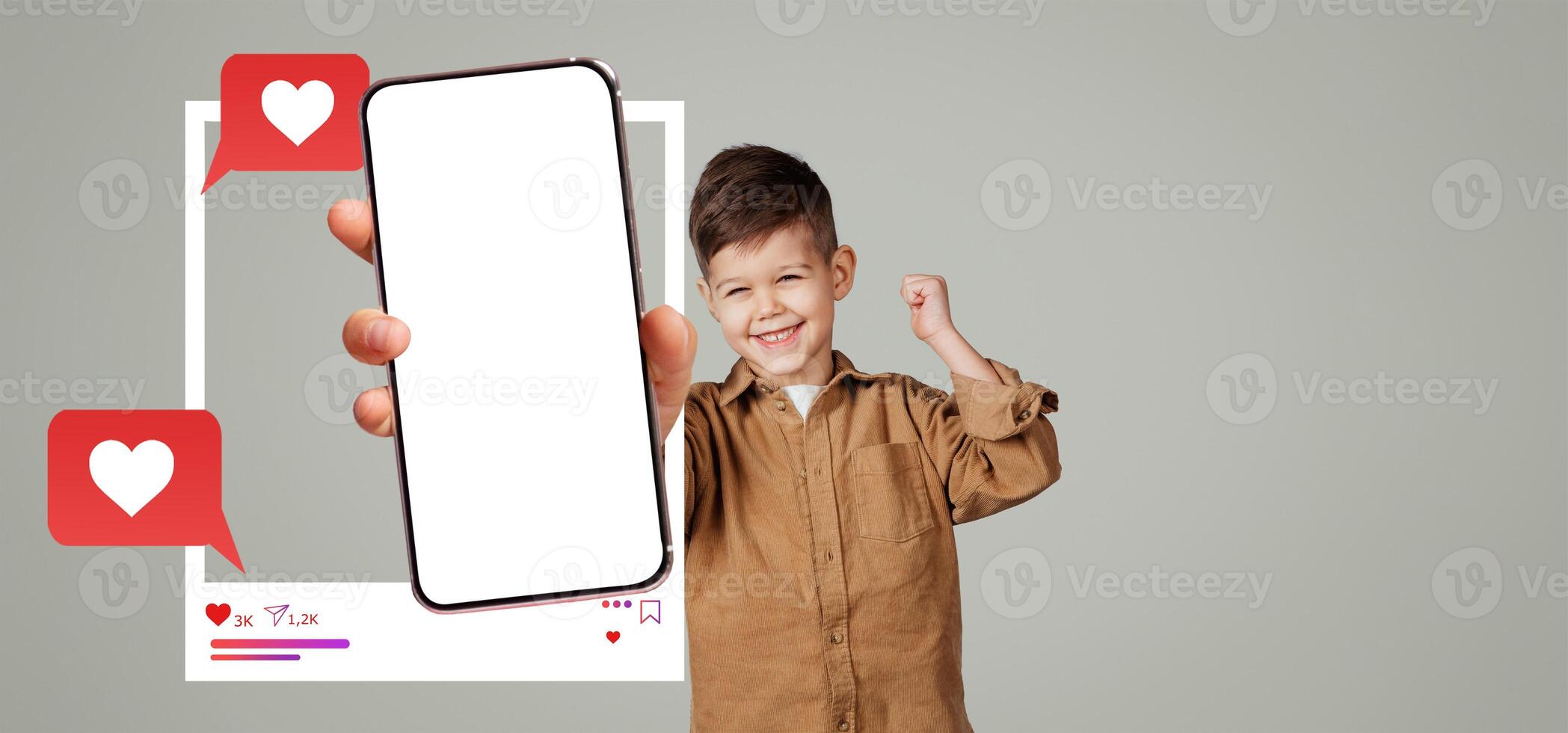 A child happily displays a smartphone with an empty screen while raising a fist in excitement. The background is plain, emphasizing the mockup for social media applications and interactions. photo