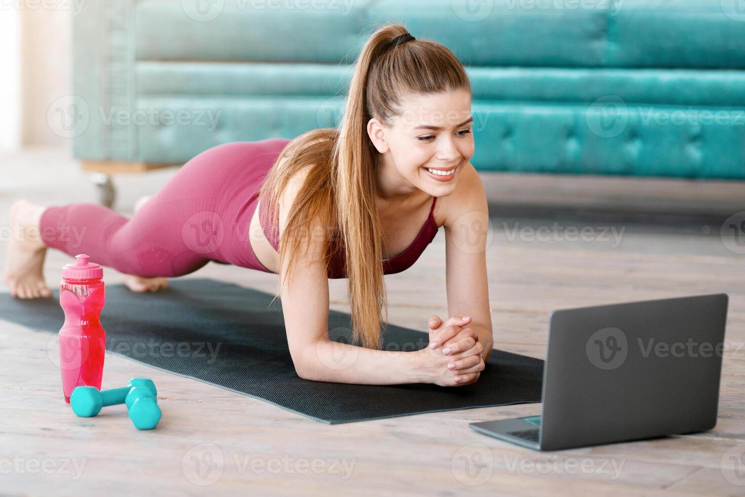 Strong Caucasian girl doing elbow plank exercise to online at home photo