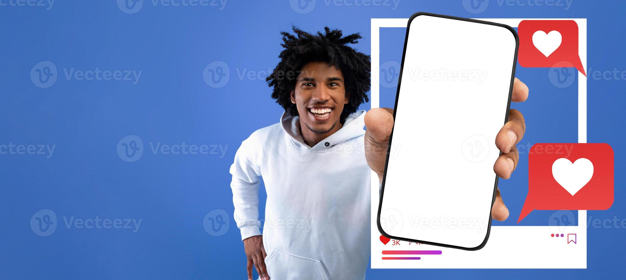 An enthusiastic influencer smiles while holding a smartphone displaying social media icons. The bright blue background enhances the vibrant energy of online interactions and connectivity. photo