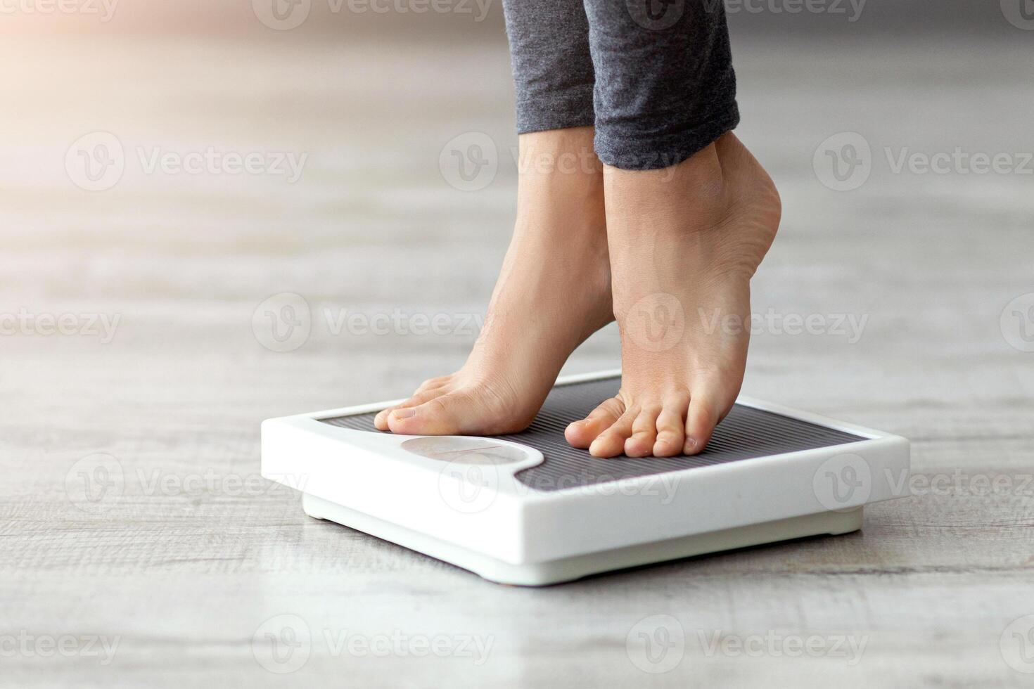 A young Indian woman weighs herself on a scale at home, focusing on fitness and a healthy lifestyle. She is committed to her workout routine and balanced diet. photo