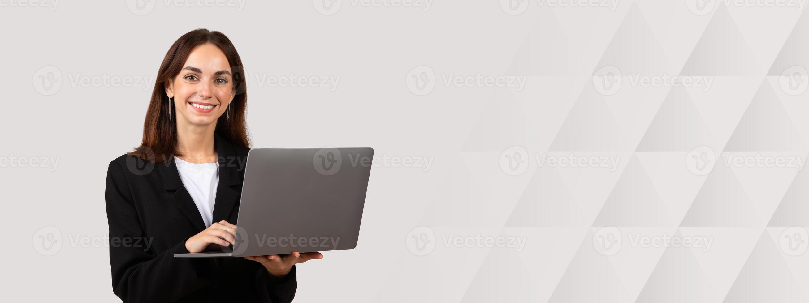 Professional millennial european businesswoman holding a laptop with a pleasant smile, ready to work, symbolizing productivity and modern technology use in business attire photo