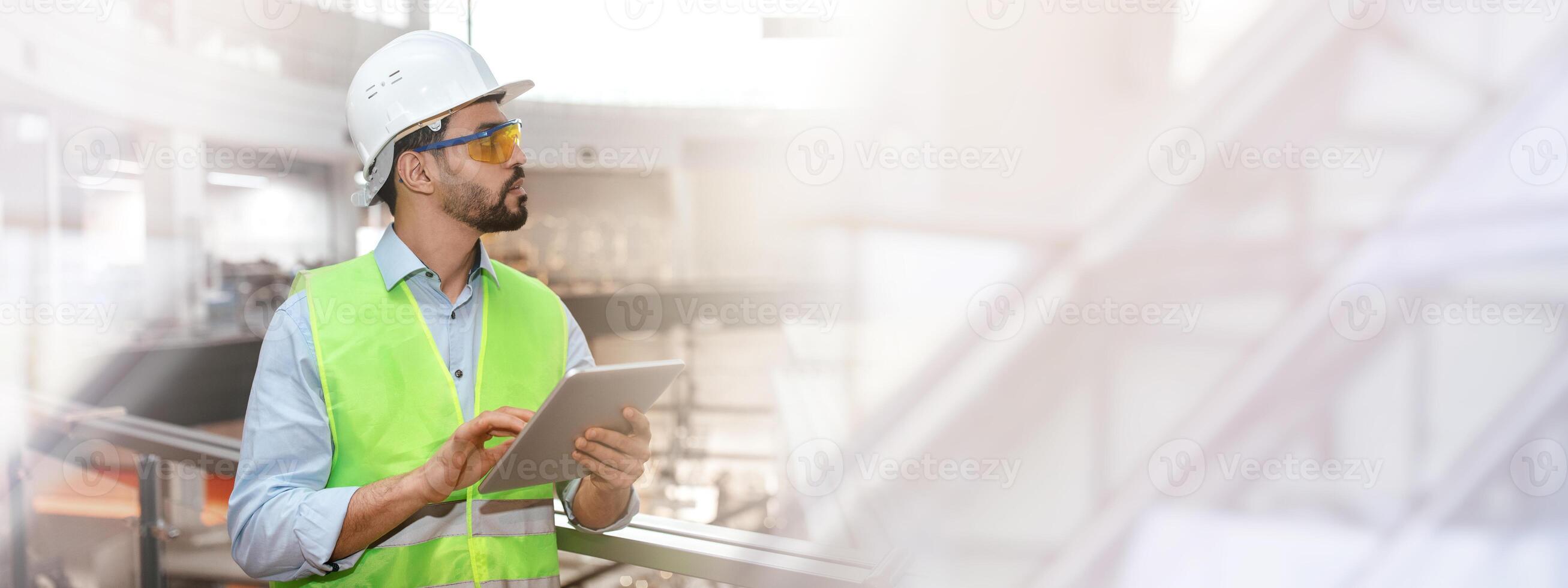 Serious pensive millennial islamic man engineer in protective uniform, glasses and hard hat with beard with tablet controls work in factory interior. Business, industry develop photo