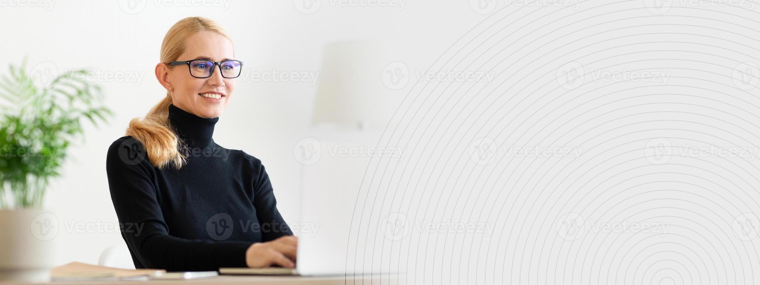 A woman with glasses is sitting at a desk in a stylish office, focused on her laptop. The bright room features minimalistic decor and lush green plants, creating a calming atmosphere, copy space photo