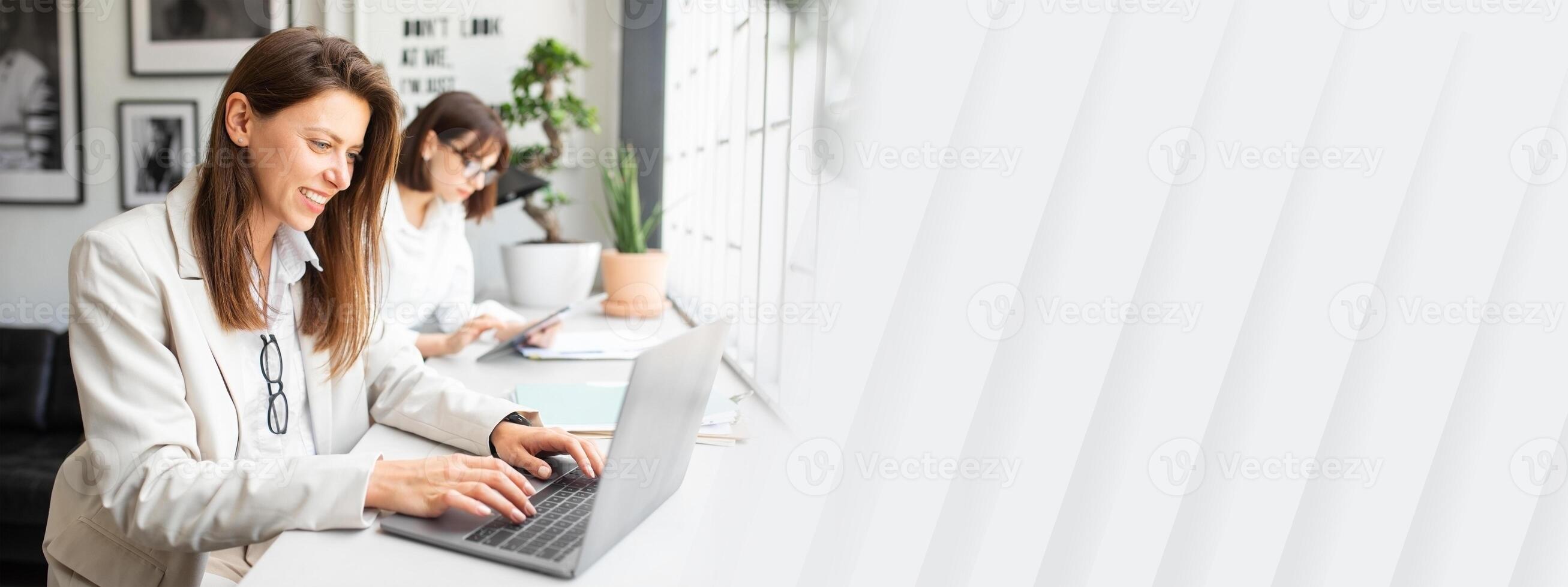 Creative young woman office workers collaborating together, working with laptop and digital tablet in office, creating businness investment plan, selective focus photo
