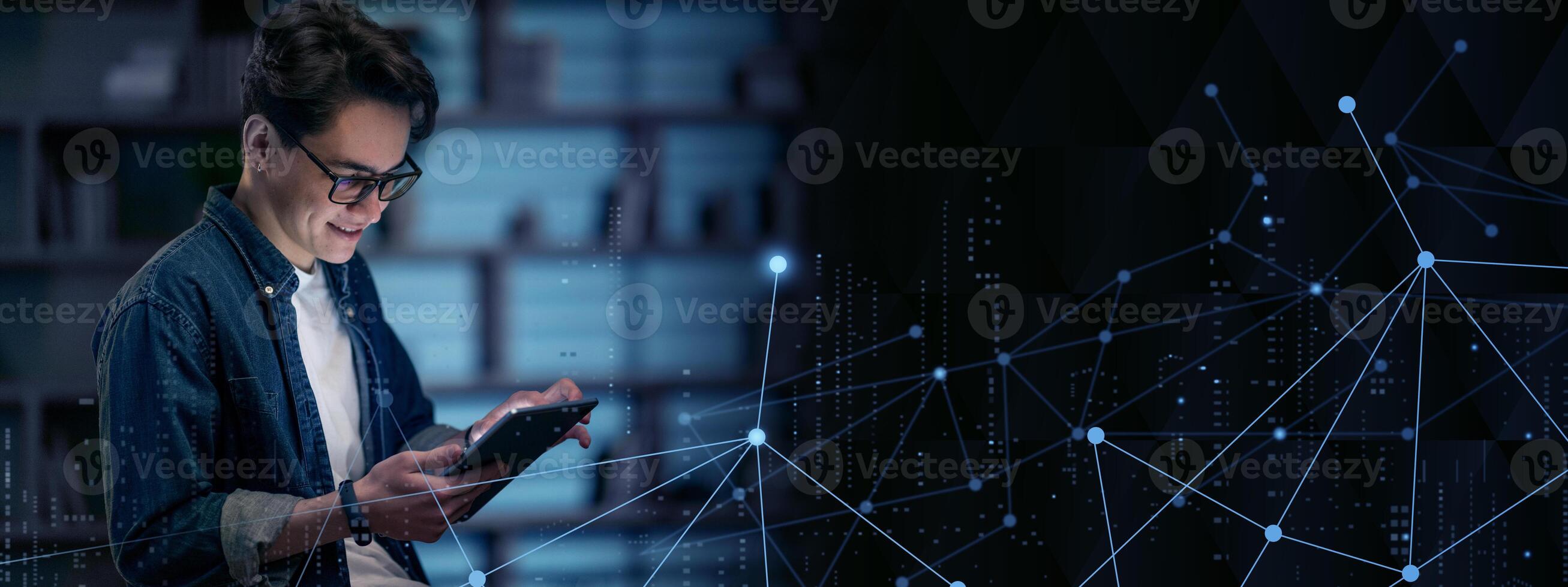 Happy millennial man in glasses use tablet, planning or visualizing future success. Smiling young guy working on pad gadget, dreaming or thinking at dark office. Business vision concept. photo
