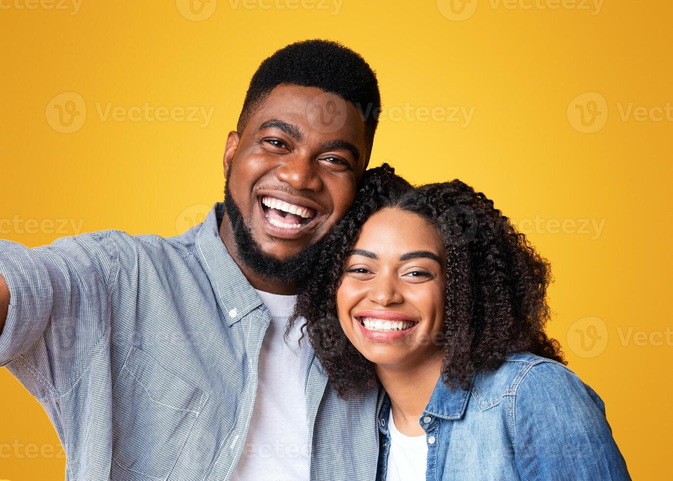 A man and woman smile widely as they stand closely together, radiating happiness. Their bright smiles and playful pose suggest a light-hearted moment filled with joy and connection. photo