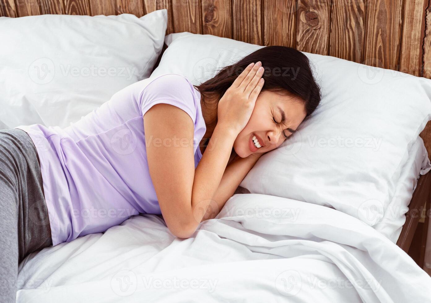 Ear Pain. Asian Girl Touching Aching Ears Suffering From Otitis Infection Lying In Bed At Home. photo