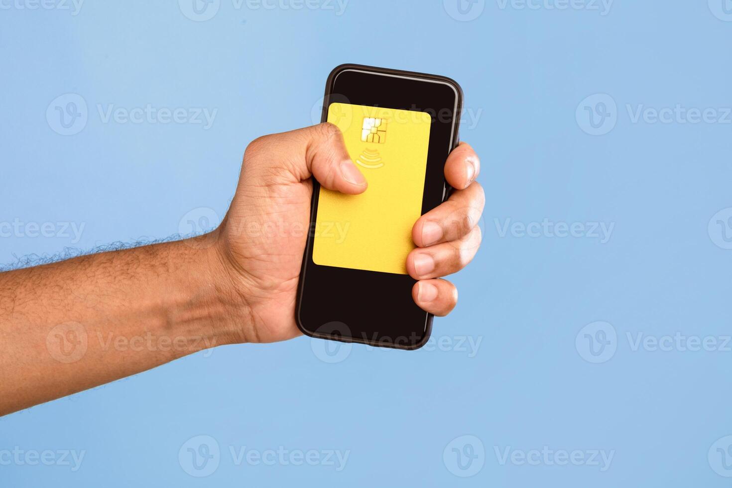 A young African American man isolates himself in a bright setting while holding a smartphone with a yellow card. The simplicity of the moment highlights modern lifestyle choices. photo