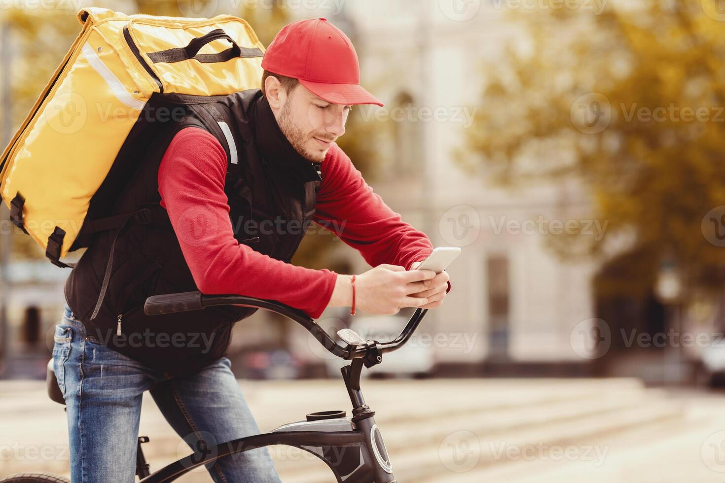 Delivery Guy In Uniform Using Cellphone Sitting On Bike In Urban Area Outdoors. Courier Service App. Copy Space photo