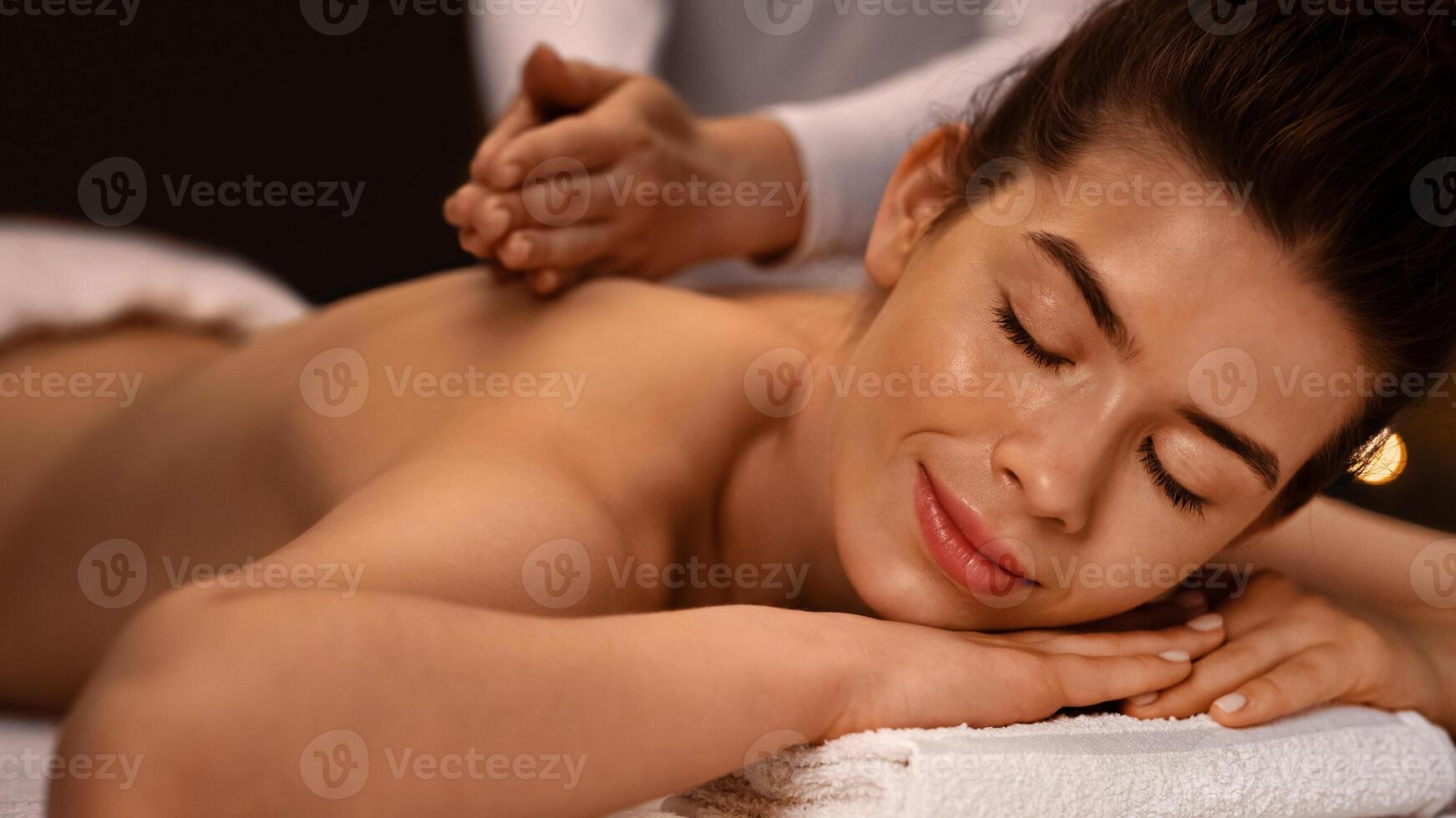 Closeup of tranquil young woman enjoying relaxing body massage at spa photo