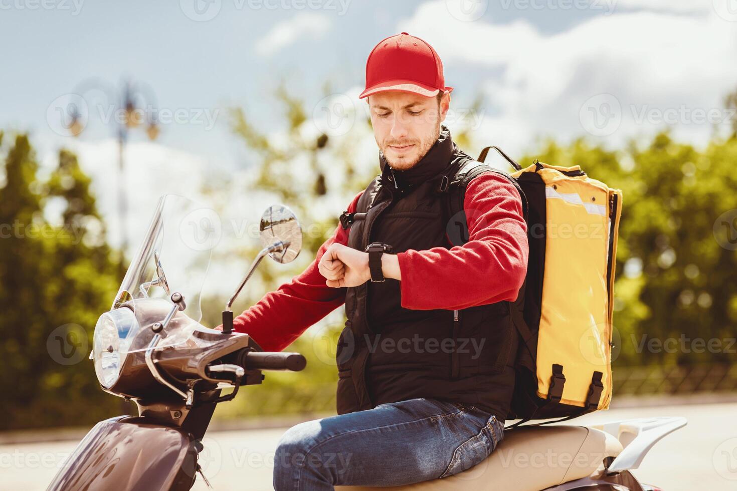 On-Time Delivery Service. Courier Guy On Scooter Checking Time On Wristwatch Delivering Food In City photo