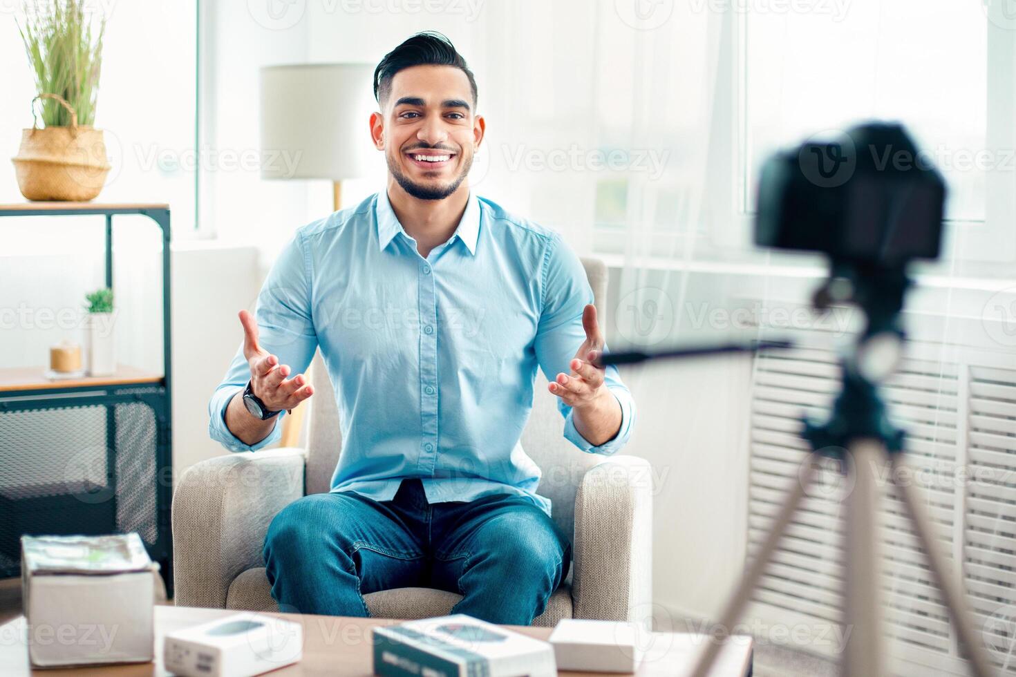 A young Arab entrepreneur sits confidently in a bright office, engaging the camera while surrounded by tech products and a relaxed atmosphere. He radiates professionalism and enthusiasm. photo