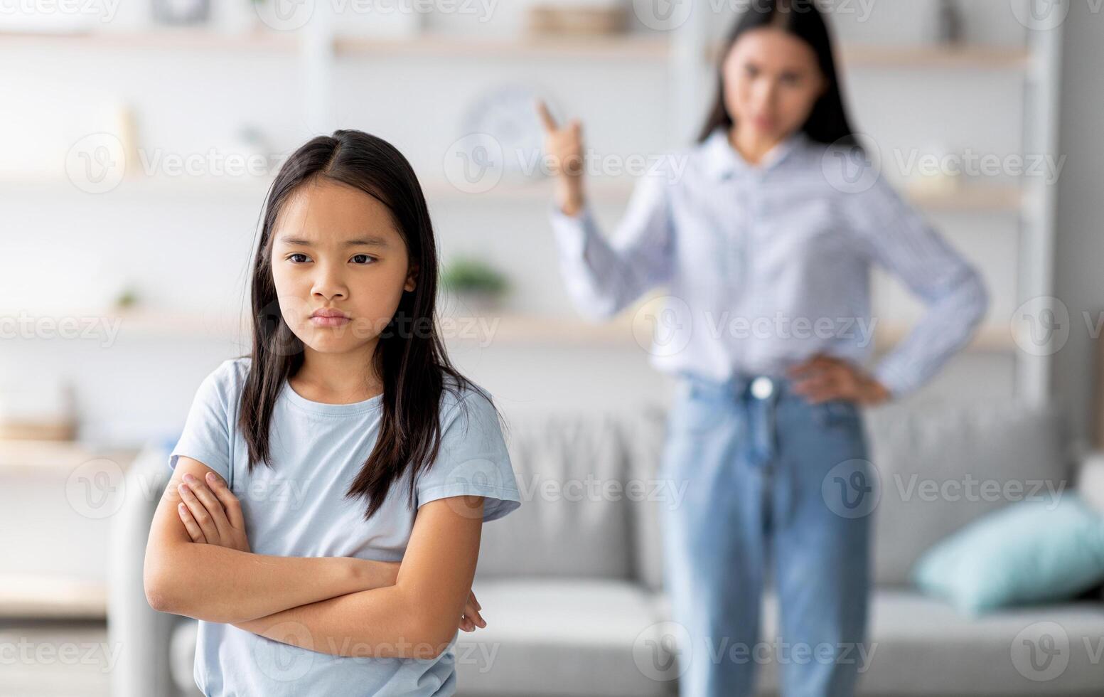 Family conflict. Mother and daughter quarreling at home, sulky child girl ignoring her mom, standing back to her with crossed arms, selective focus, copy space photo