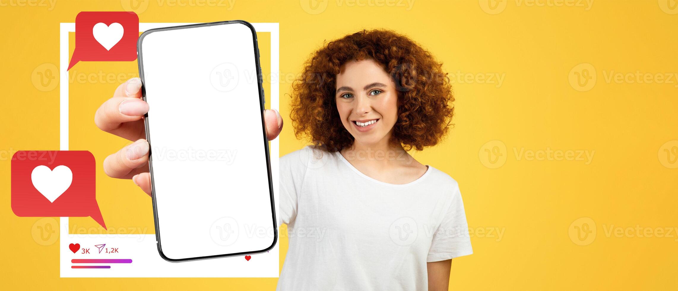 A cheerful influencer with curly hair holds a smartphone against a bright yellow background. The screen is blank, perfect for showcasing social media interactions like likes and messages. photo
