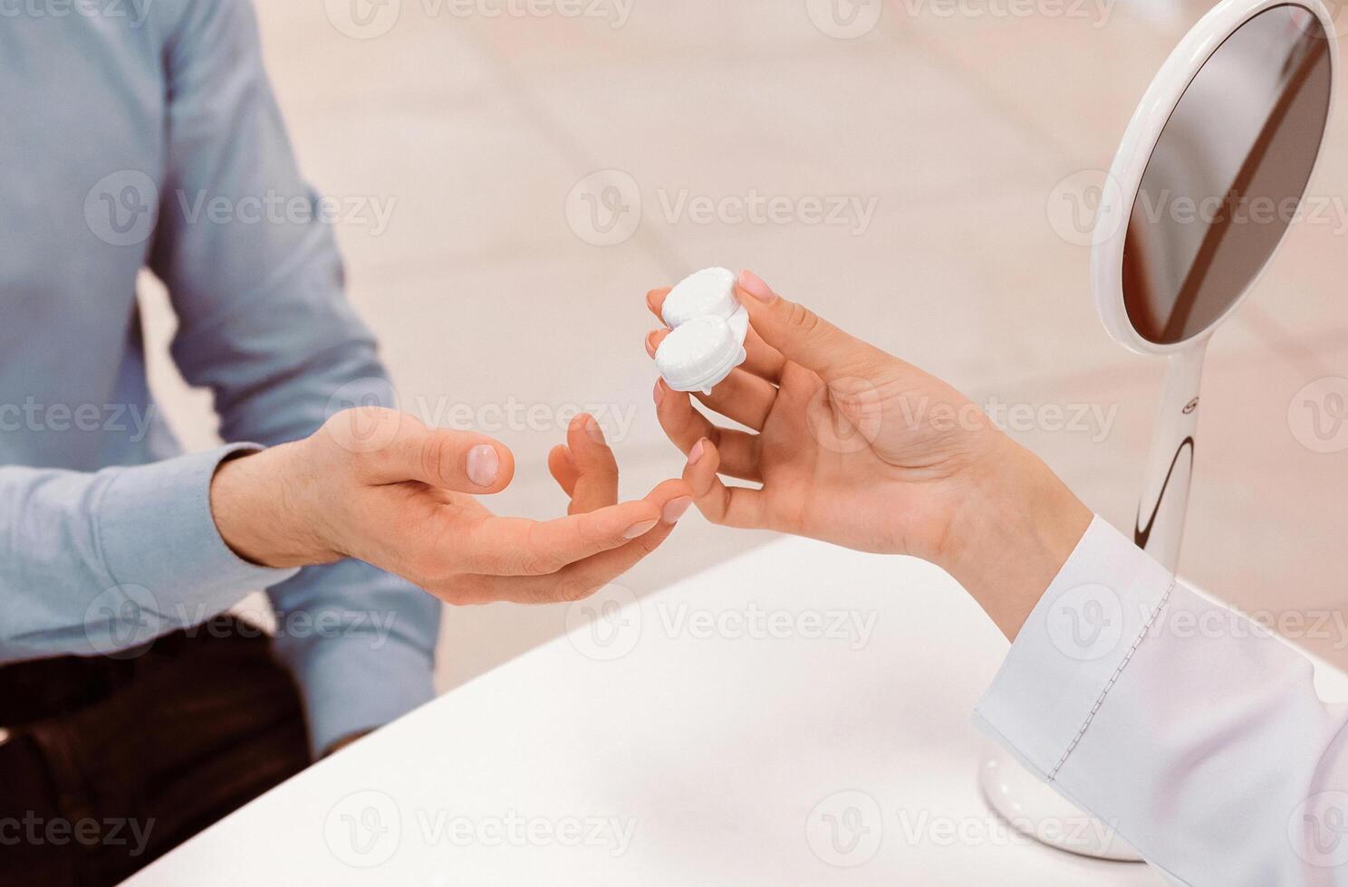 A patient is handed a contact lens case by an eye care professional in a bright clinic. The professional demonstrates proper lens handling to ensure safe usage. photo