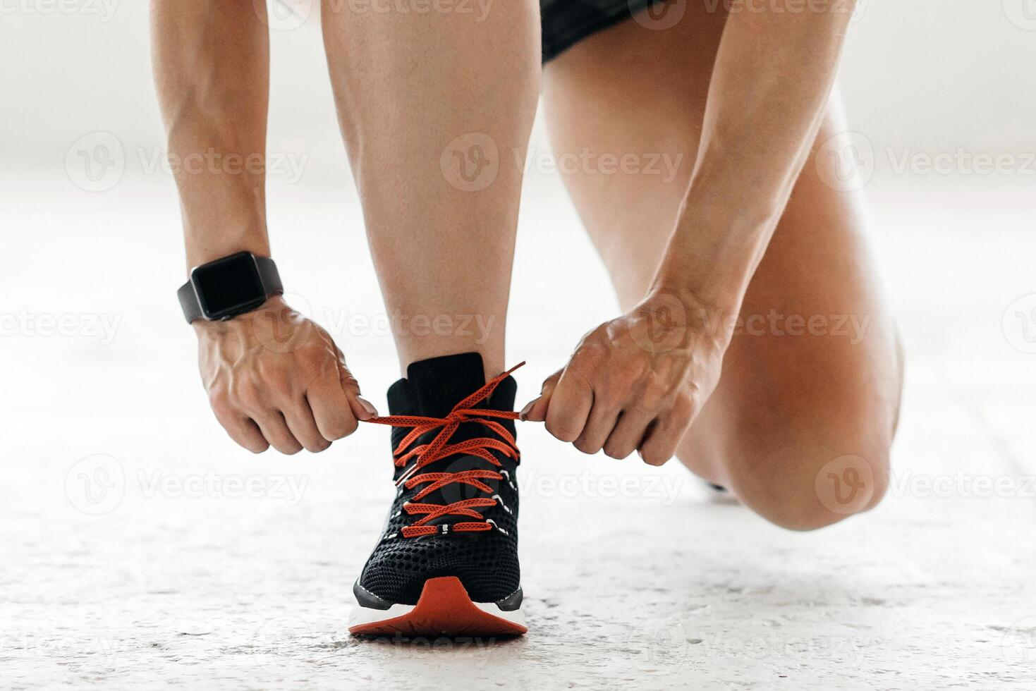 Preparation for marathon. Woman with smart watch tying shoelaces on sneakers, sitting on floor in gym or living room, panorama, copy space photo