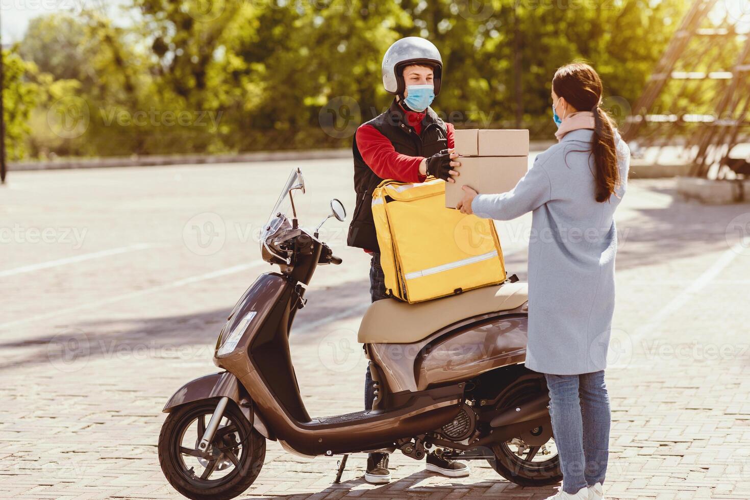 Courier Service. Delivery Man Giving Woman Food Boxes With Lunch Ordered In Restaurant Standing With Scooter, Wearing Protective Mask Outside photo