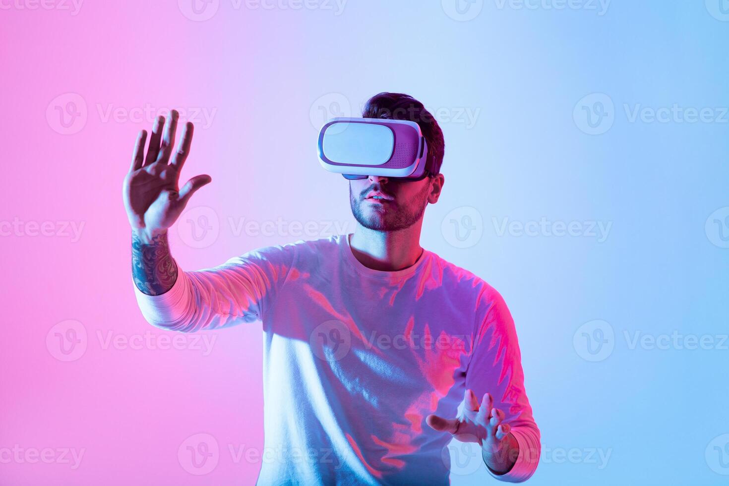 A person explores a virtual reality experience, wearing a headset while interacting with their surroundings. The vibrant pink and blue lights create an immersive atmosphere. photo