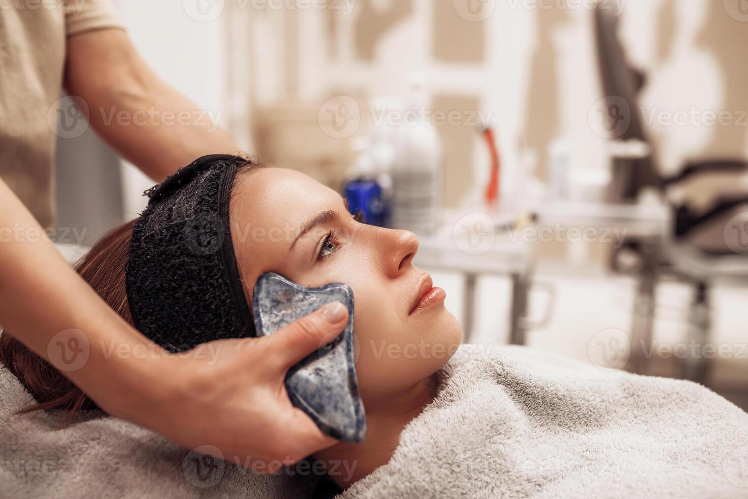Woman receiving facial massage in beauty salon. photo