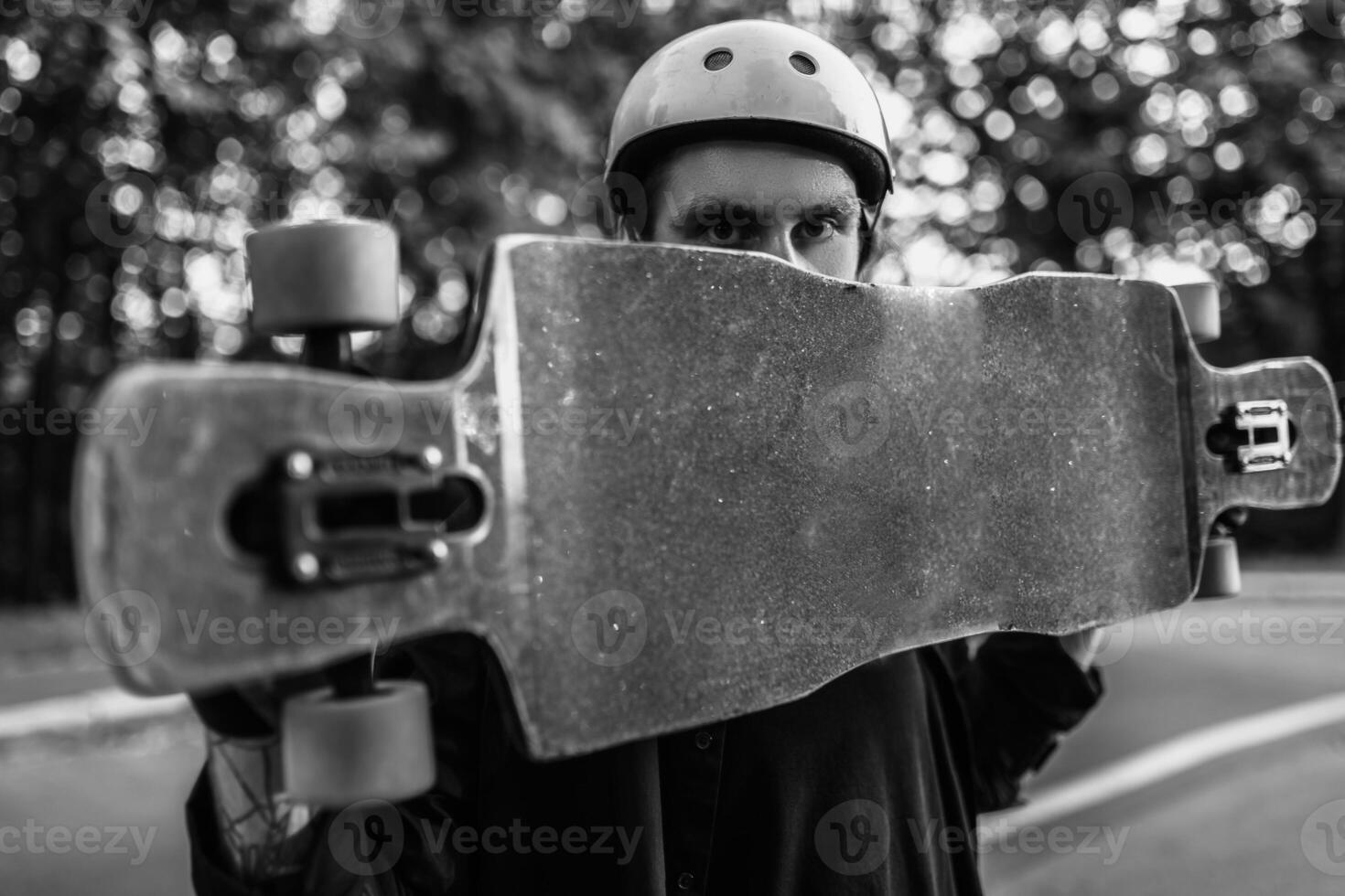 The guy is holding a longboard. Black and white portrait of an athlete. photo