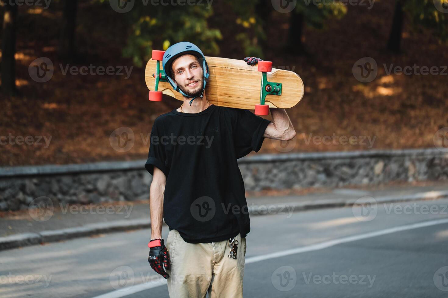 Portrait of a guy with a longboard on his shoulder. Skateboarding in summer. photo