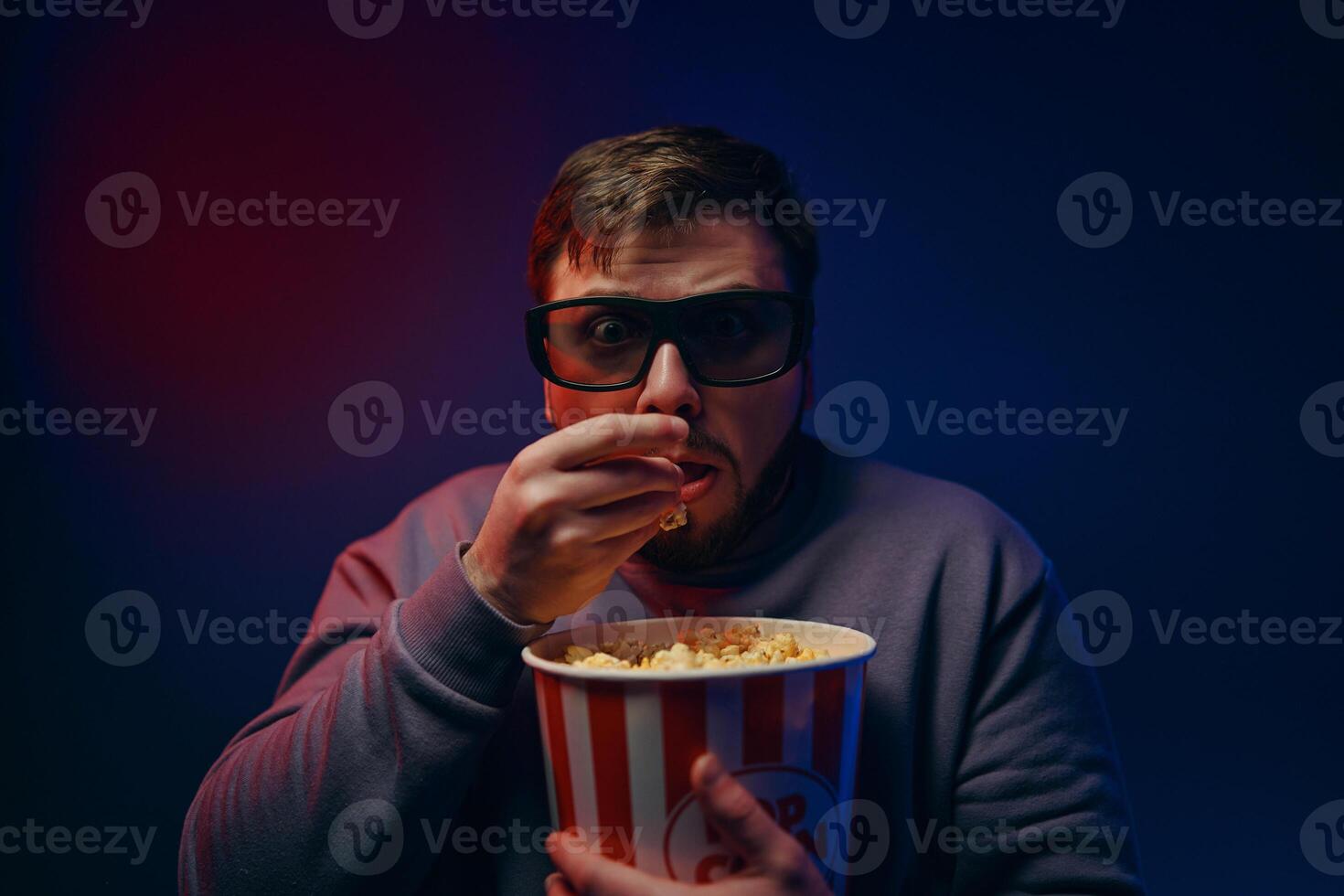 A man is watching a scary movie. Watching a movie with popcorn. photo