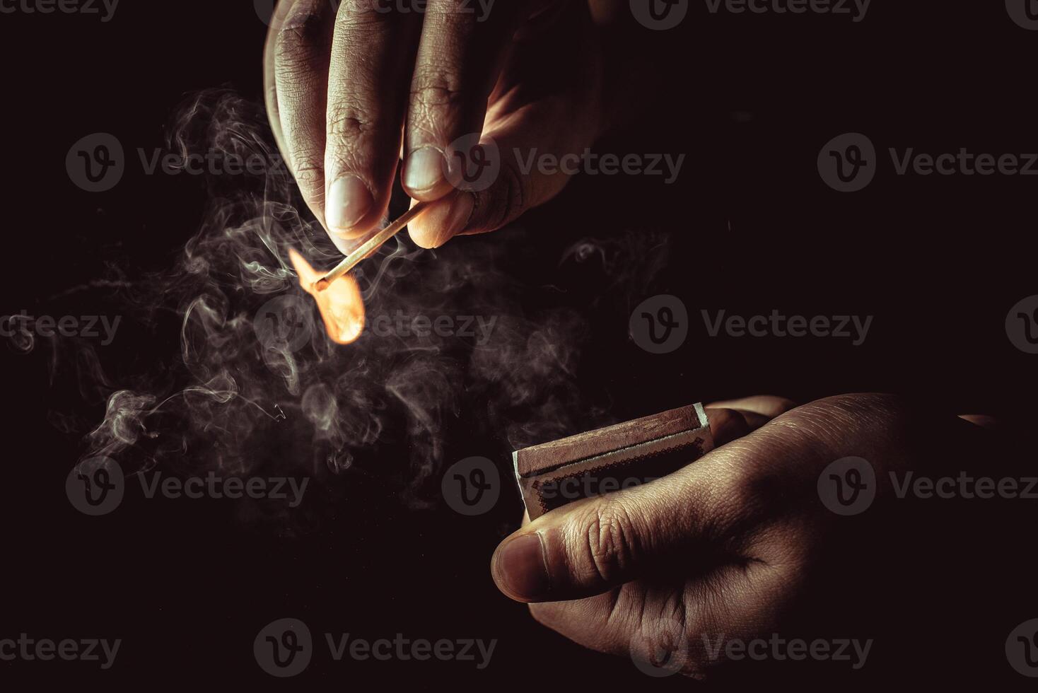 Playing with fire. A burning match in a man's hand on a black background. photo