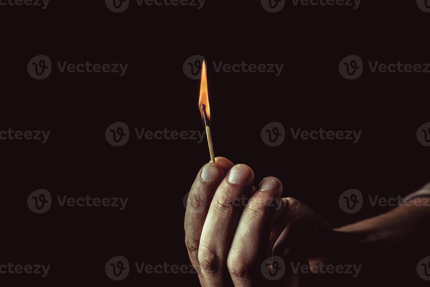Playing with fire. A burning match in a man's hand on a black background. photo