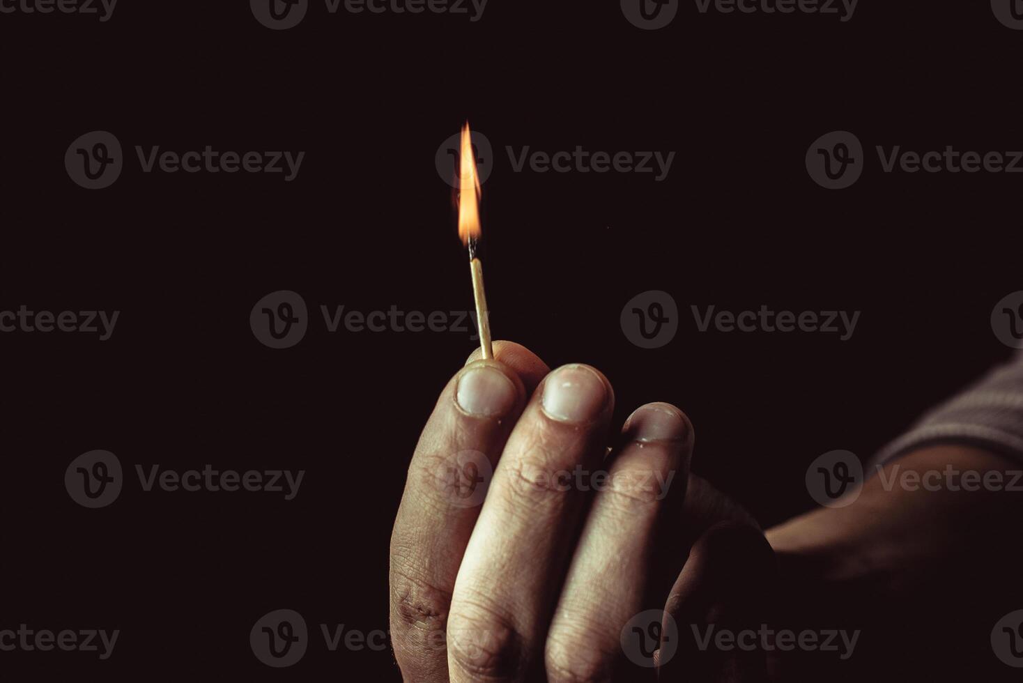 Playing with fire. A burning match in a man's hand on a black background. photo