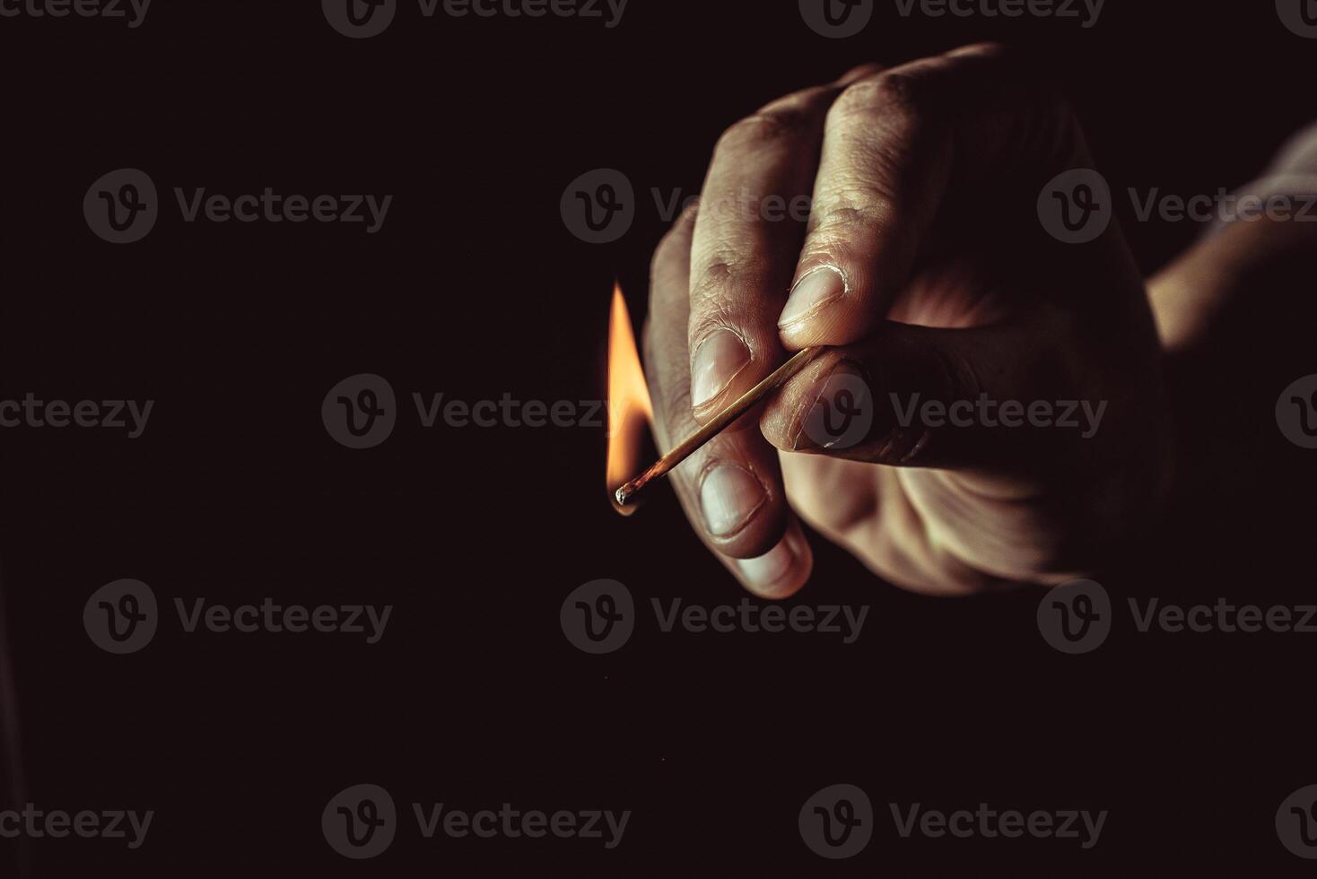 Playing with fire. A burning match in a man's hand on a black background. photo