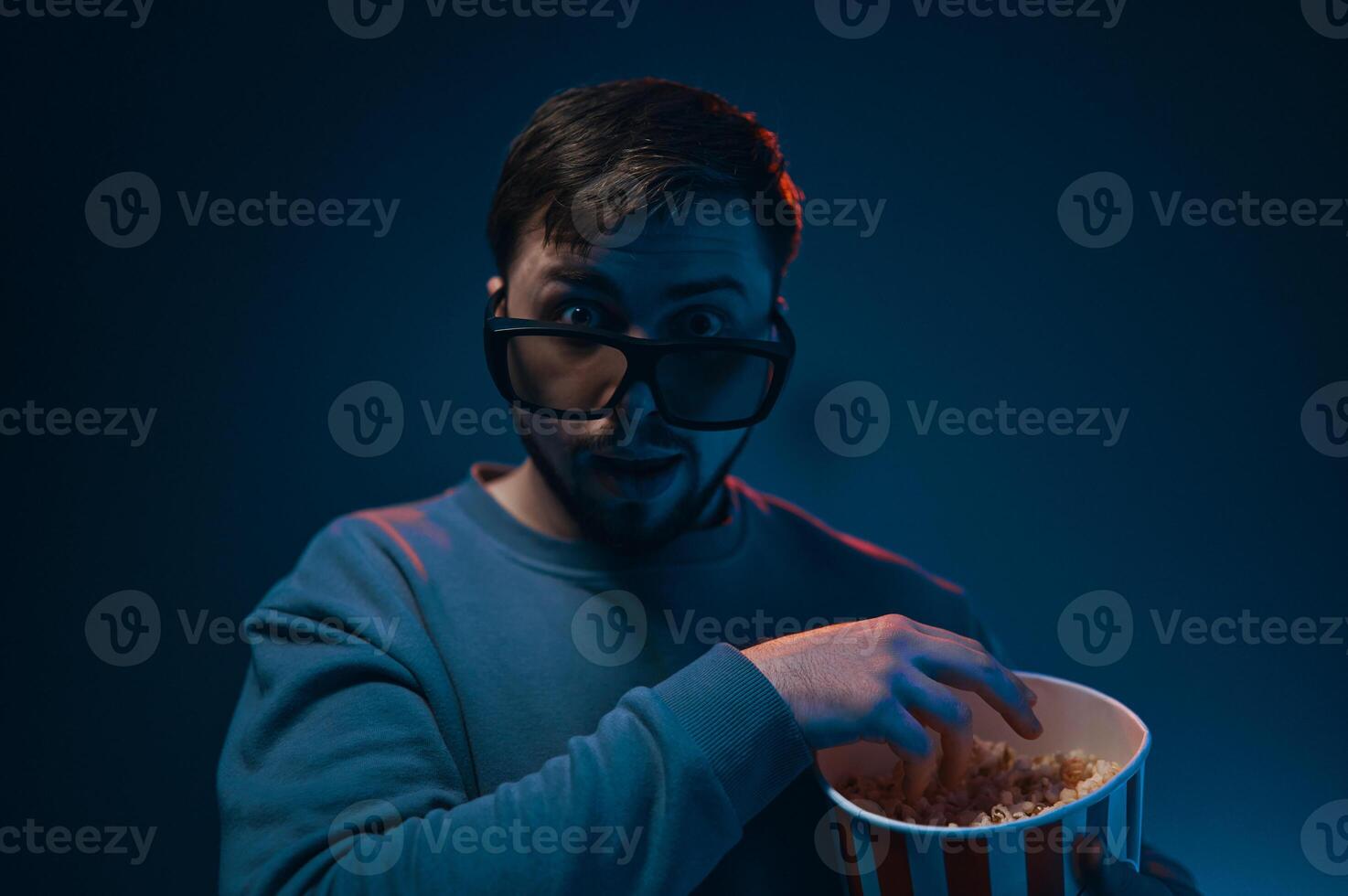 Man with surprised expression and popcorn. Emotion while watching a movie. photo